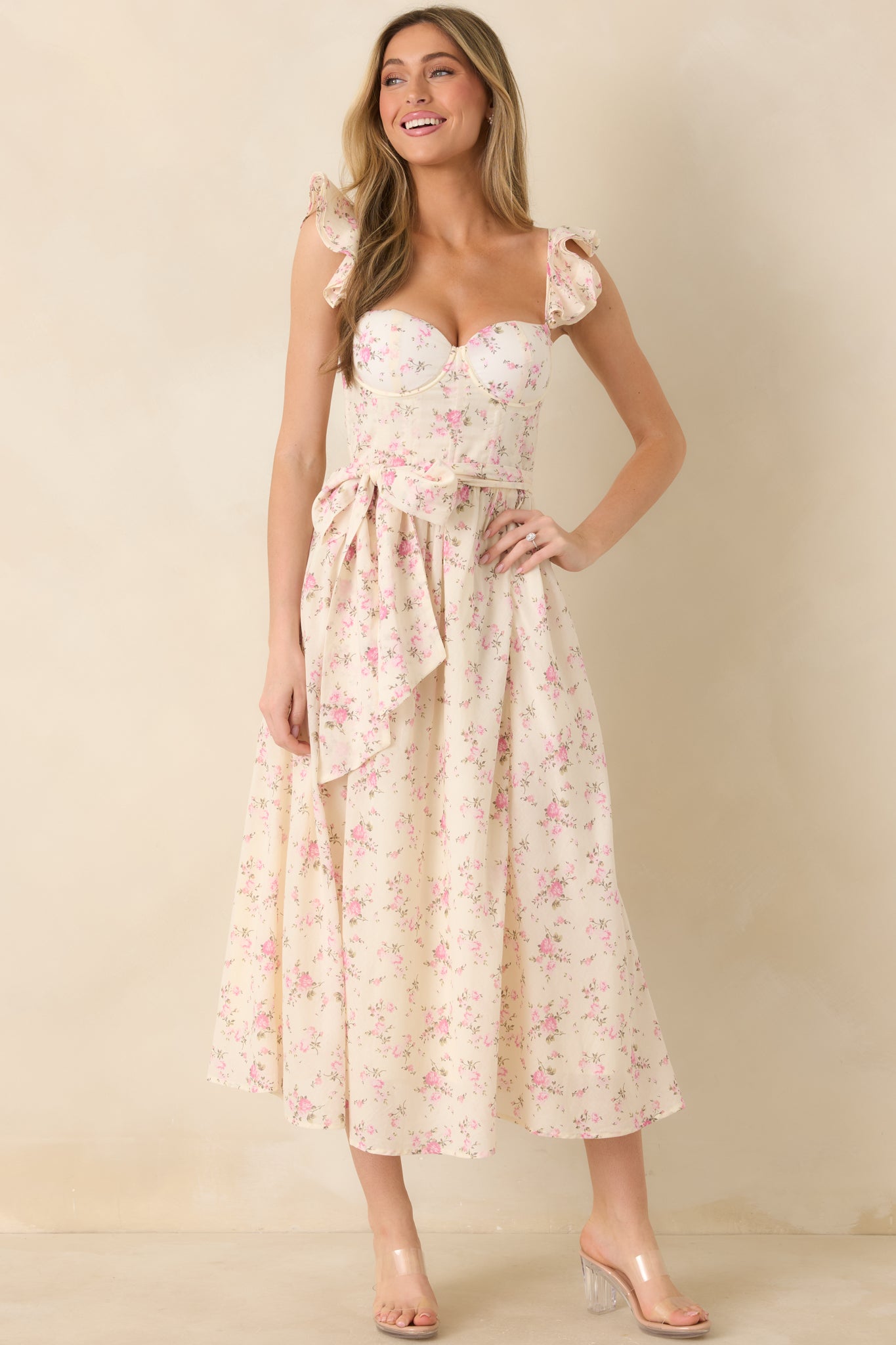 Light pink floral maxi dress with structured bust and smocked back panel, shown from the front with flowing silhouette.