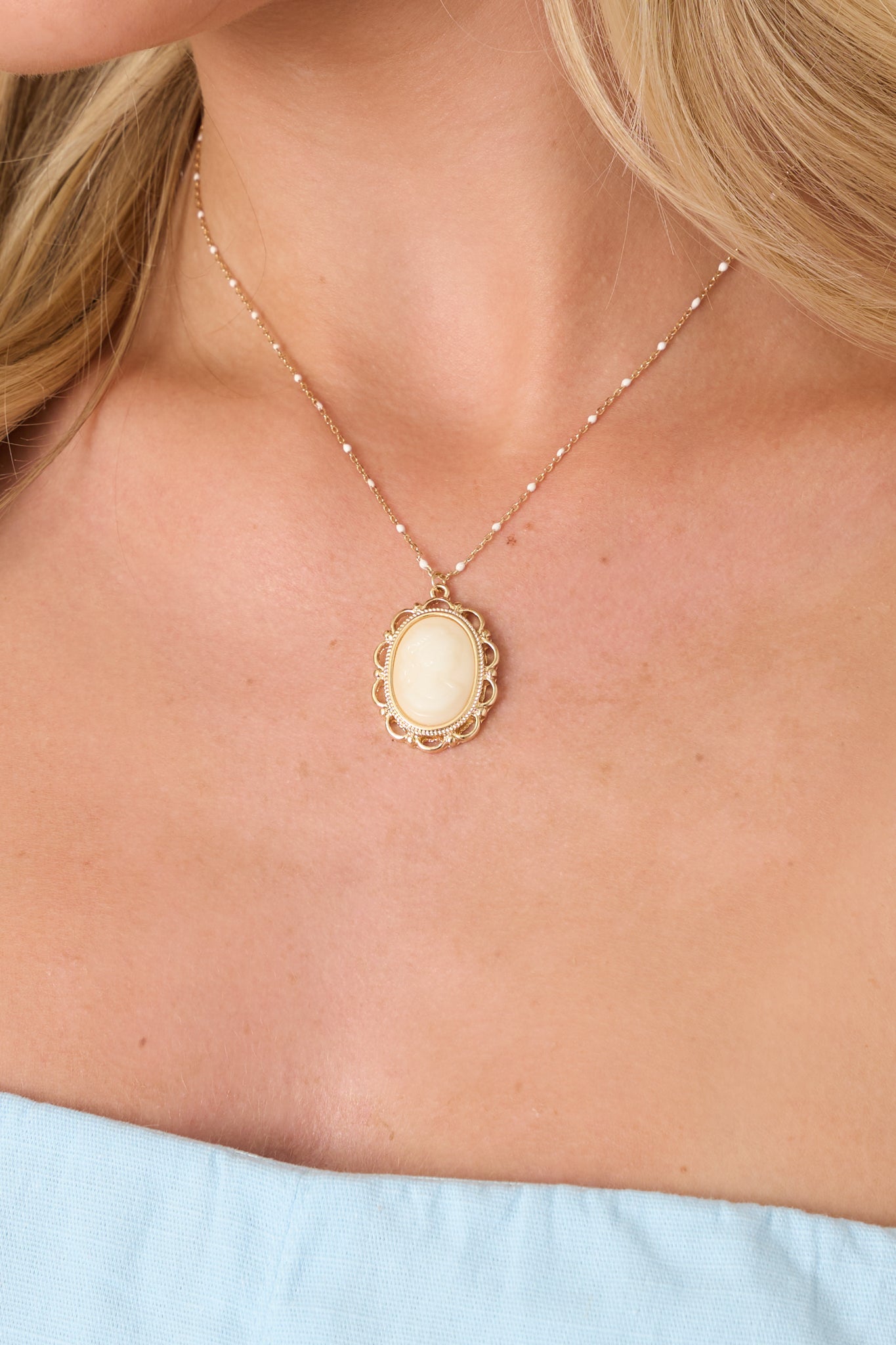 Close-up of carved ivory cameo, intricate gold frame, and subtle beaded accents on fine gold chain.