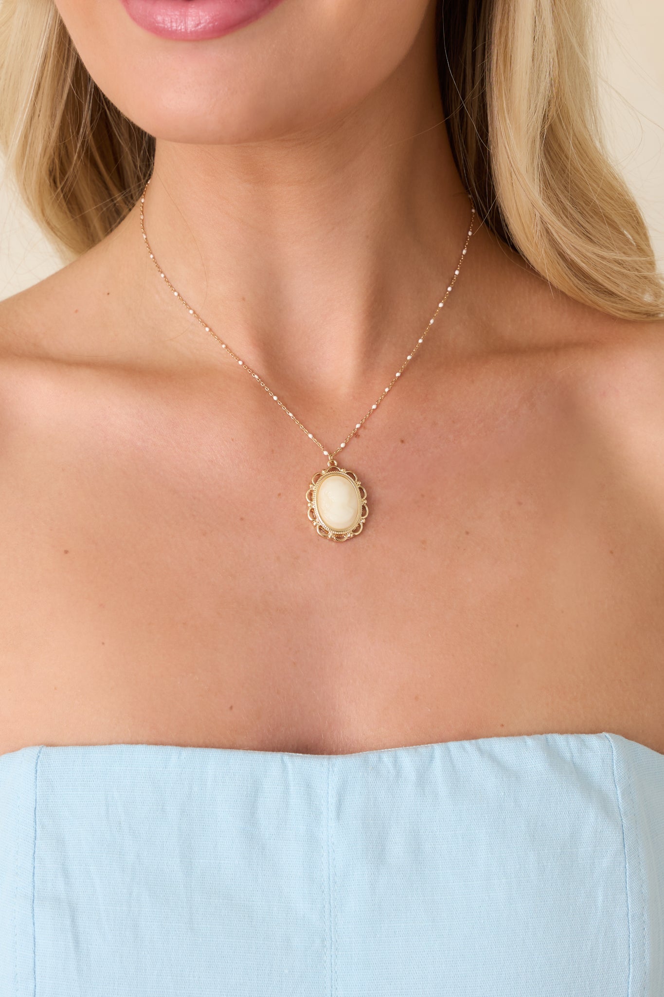 Gold necklace with ivory cameo pendant framed in intricate vintage-inspired detailing.