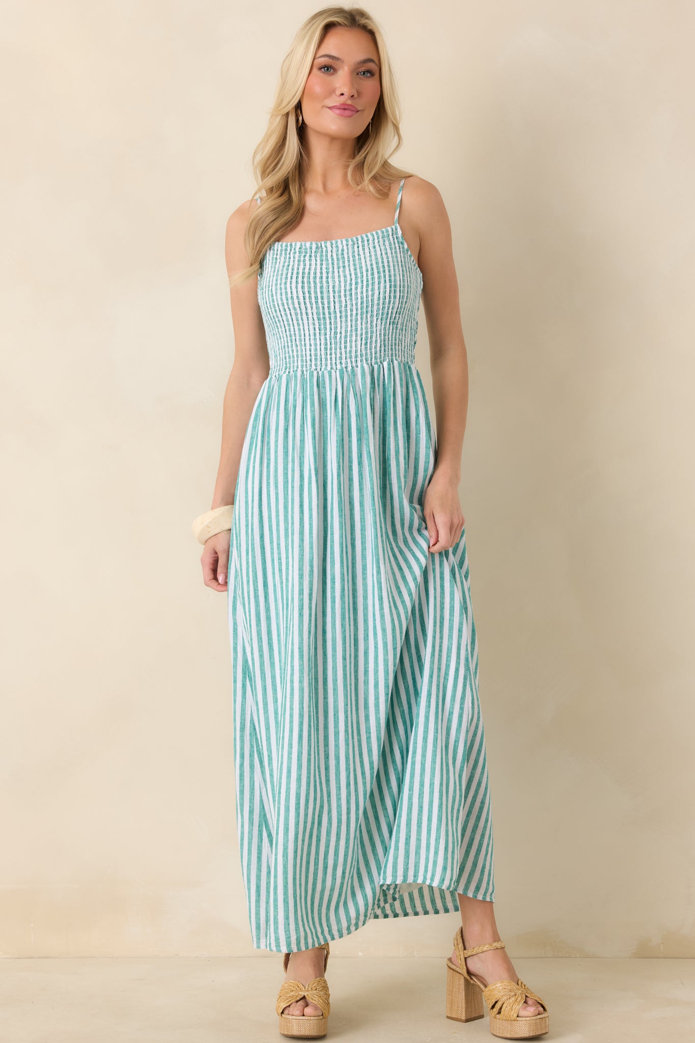 Front-facing view highlighting the flowing movement of a green-striped linen maxi dress with thin straps.