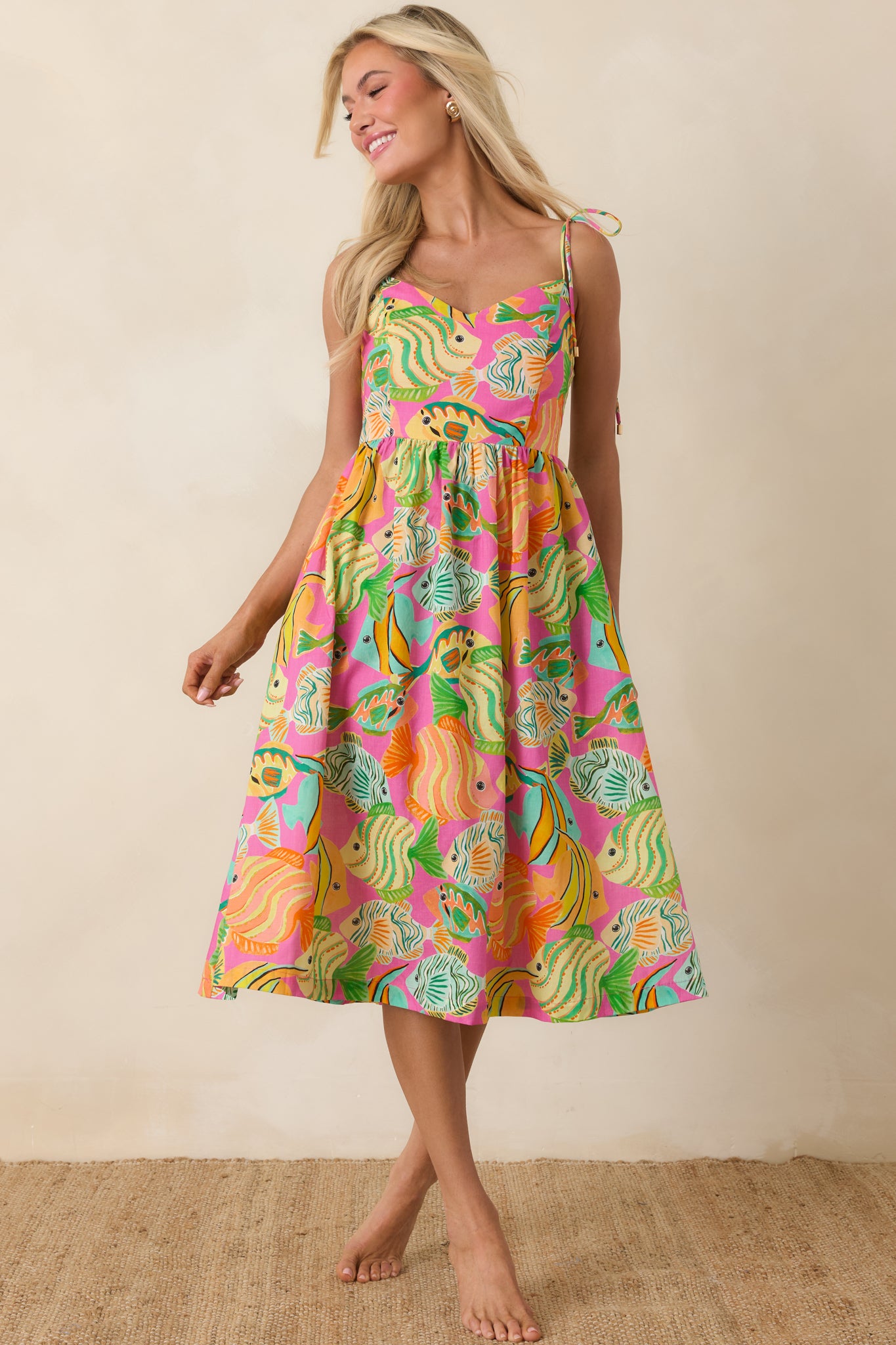 Breezy midi dress featuring vibrant fish and ocean-inspired print in bold pink, green, and orange.
