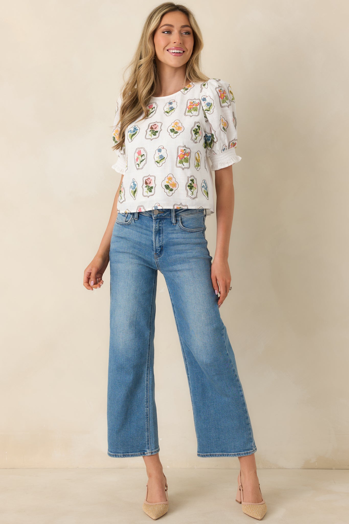 Full-length front view of the ivory embroidered top highlighting the round neckline and puff sleeve silhouette.