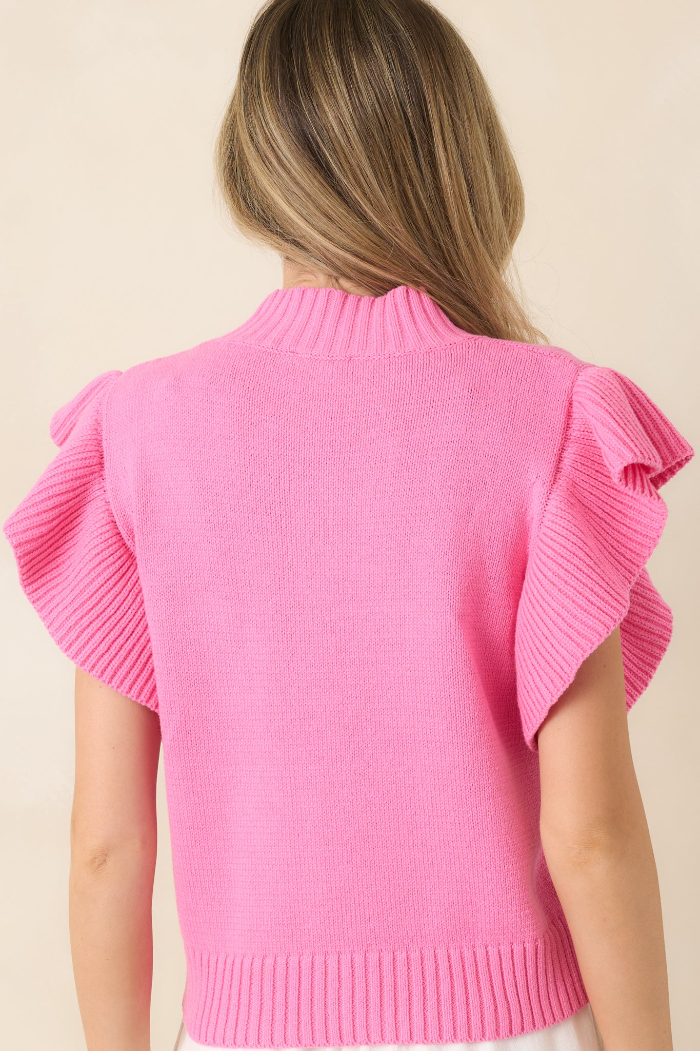 Hot pink knit top displaying a smooth rear silhouette with ribbed hem and flutter sleeves.