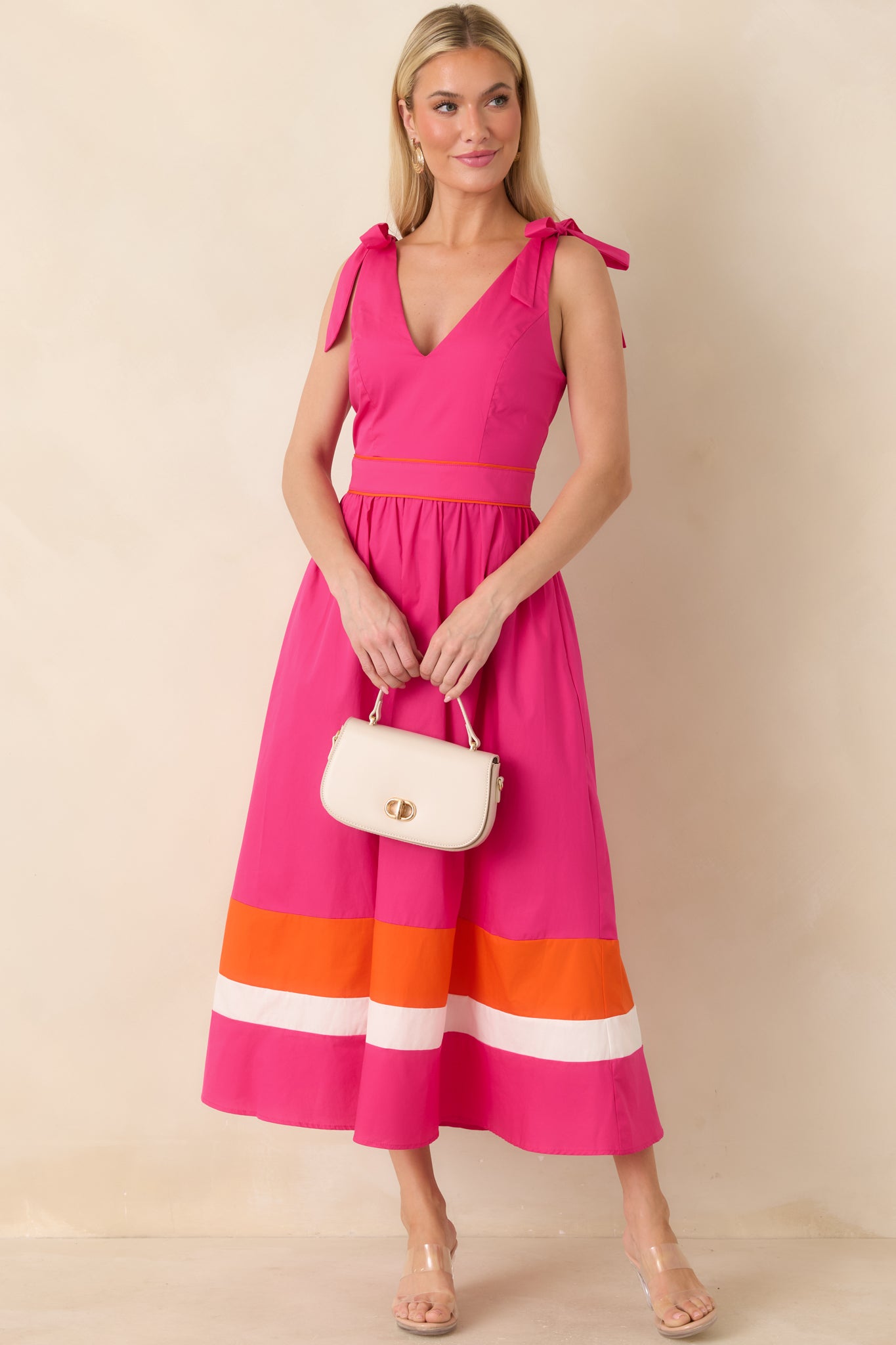 Bright fuchsia midi dress featuring adjustable shoulder ties and orange ivory hem detail.