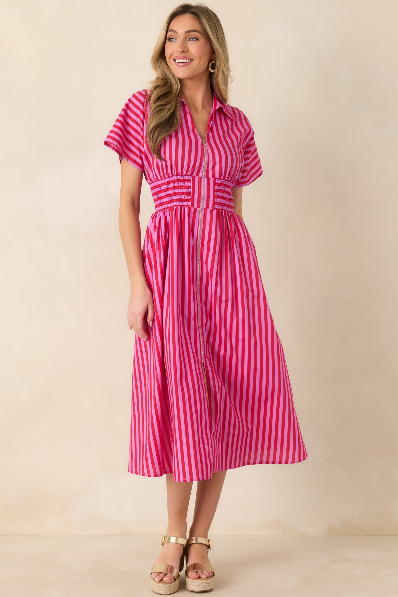 Pink and red striped A-line midi dress designed with short sleeves, functional pockets, structured collar, and a stretch smocked waistband.