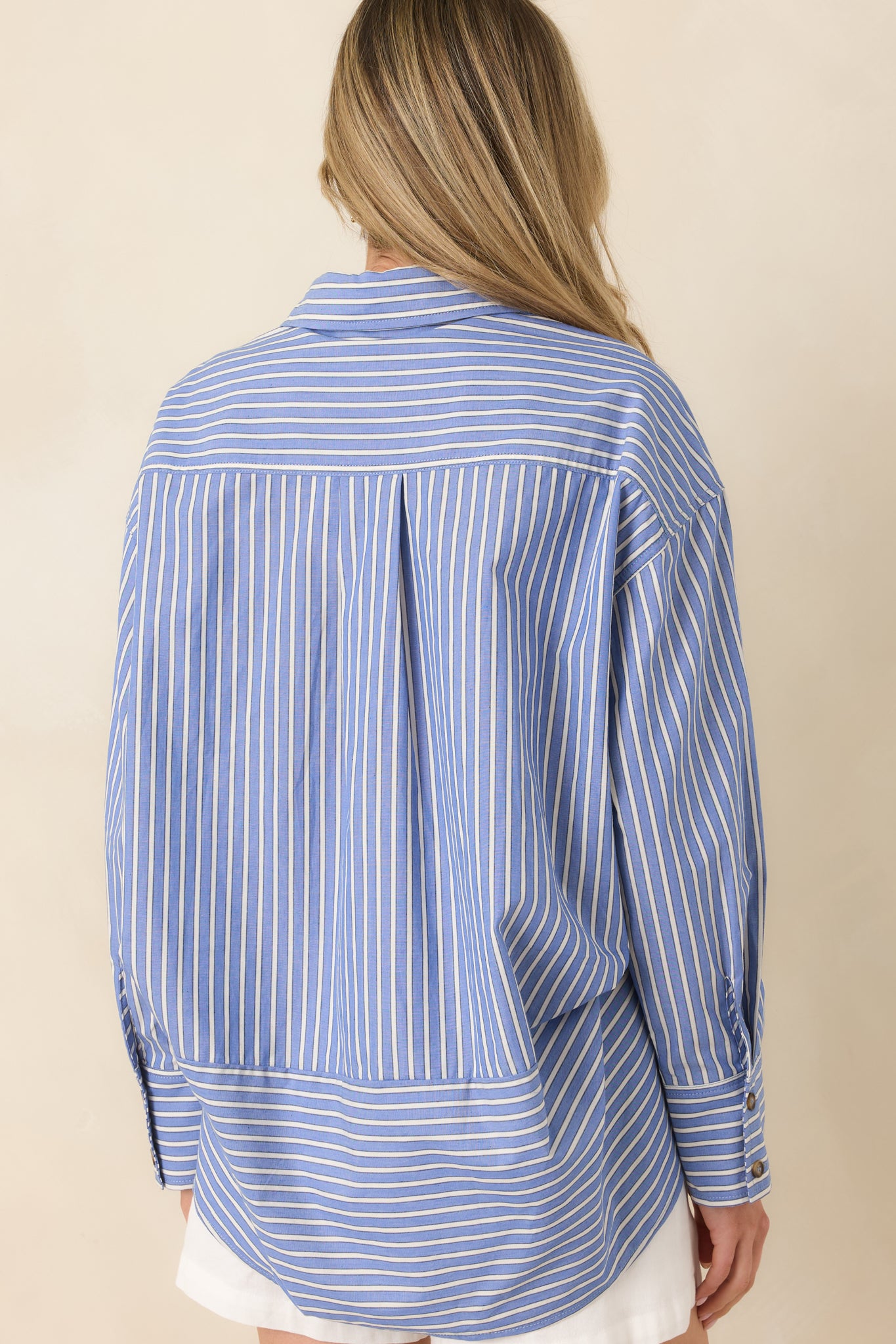 Back view of the navy striped shirt featuring long sleeves, relaxed fit, and smooth scoop hem.