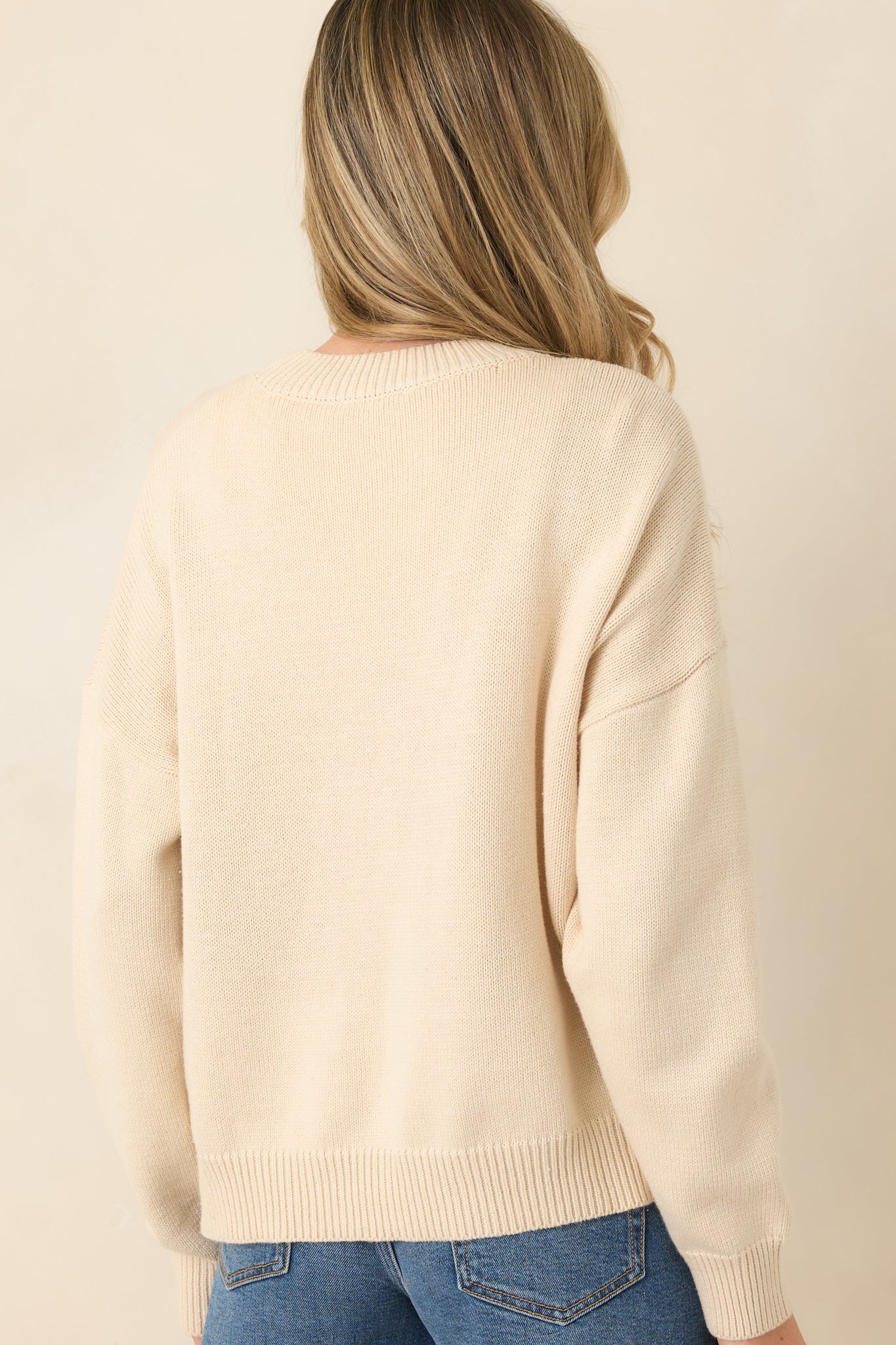 Rear view of the ivory knit sweater showing the relaxed silhouette and smooth drop-shoulder design.