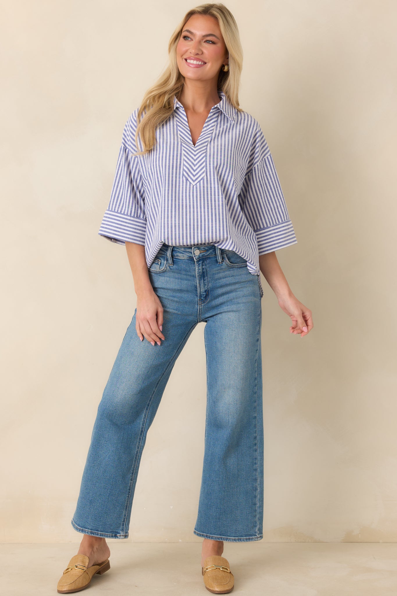 Full-body view showing the blue and white striped blouse styled untucked for a casual, modern finish.