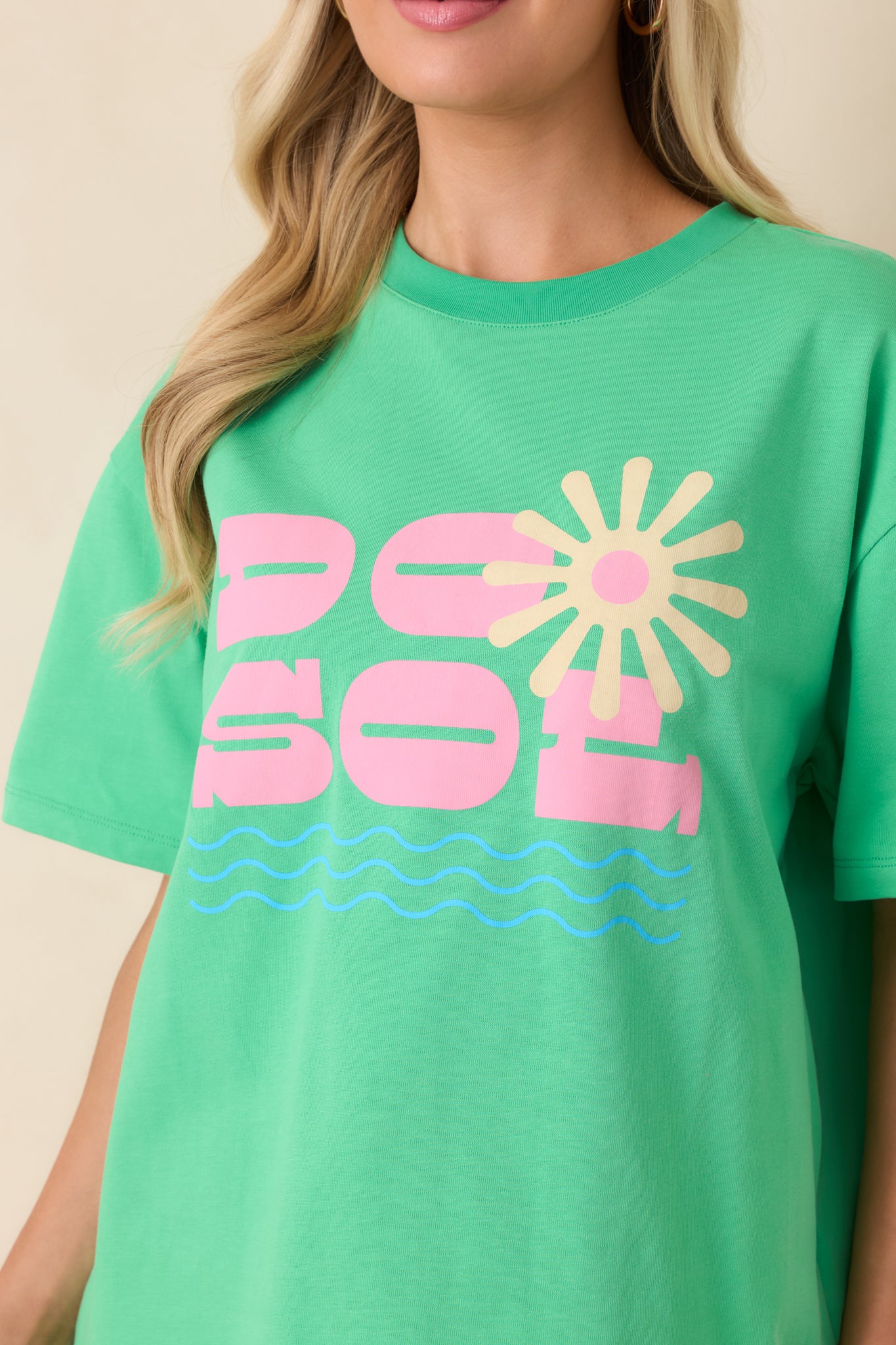 Close-up of the cotton fabric showcasing the vibrant pink “DO SOL” lettering layered over a sunburst graphic with fine wave detailing and a soft, breathable texture.