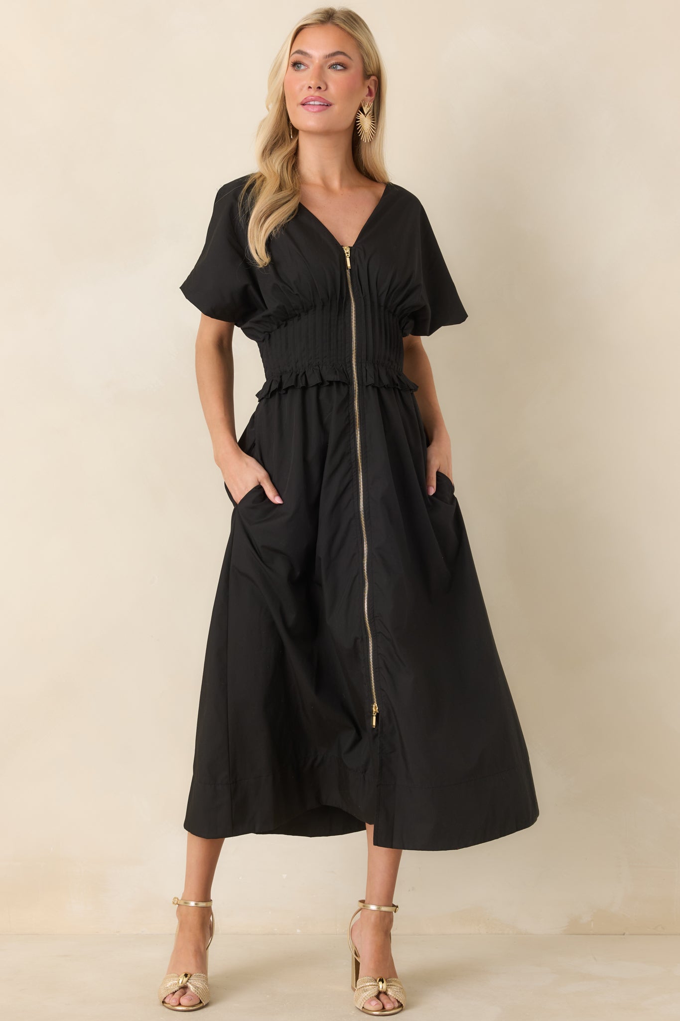 Black woven maxi dress with a V-neckline, short sleeves, and wide smocked waistband with ruffled trim.