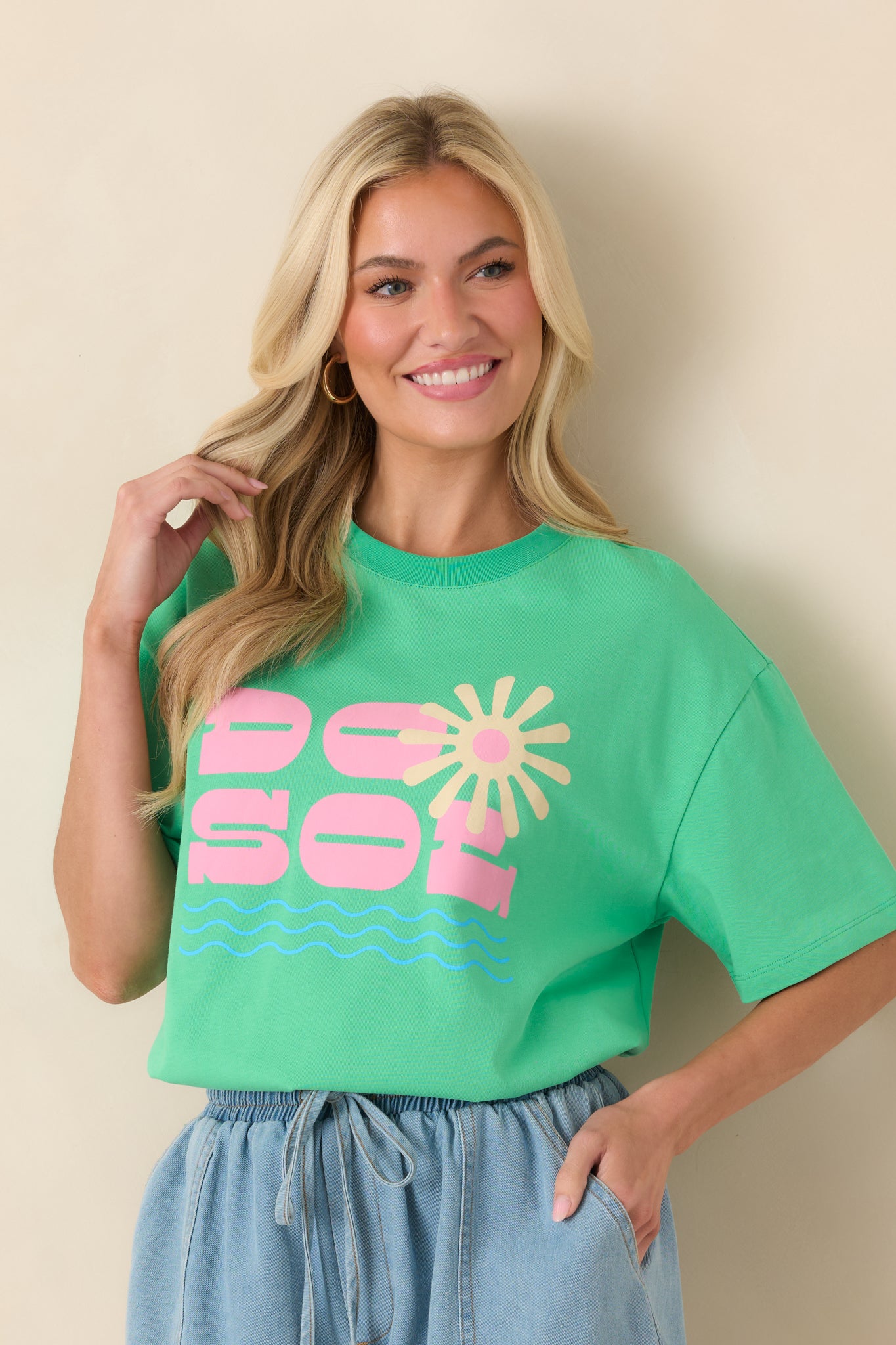 Front of the cotton tee highlighting the vivid pink “DO SOL” lettering layered over a radiant sunburst graphic with subtle wave accents.