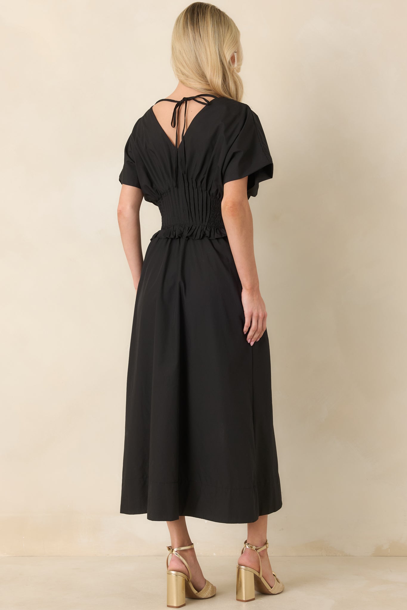 Rear view of the black woven maxi dress showing the flowing A-line skirt and smooth, structured fit.
