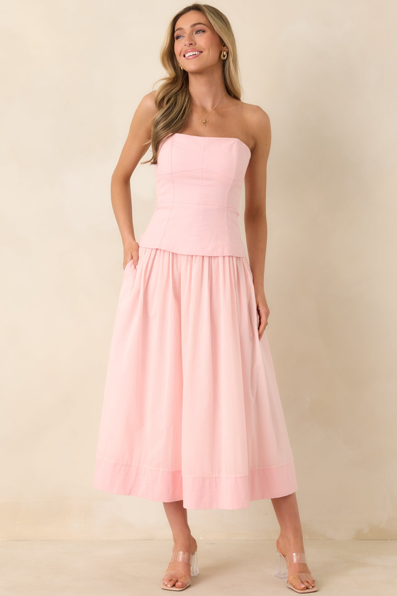 Flattering pink dress with paneled bustier top, spaghetti straps, and a voluminous gathered skirt finished with practical side pockets.