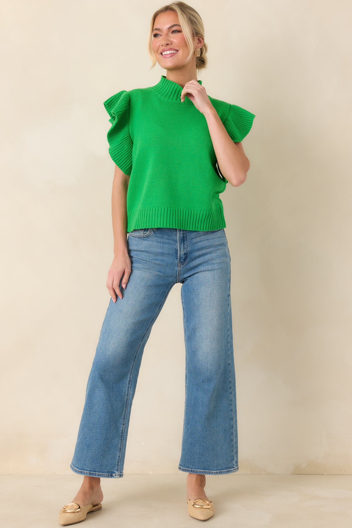 Knit green top showcasing a mock neckline and layered ribbed flutter sleeves with subtle texture throughout.