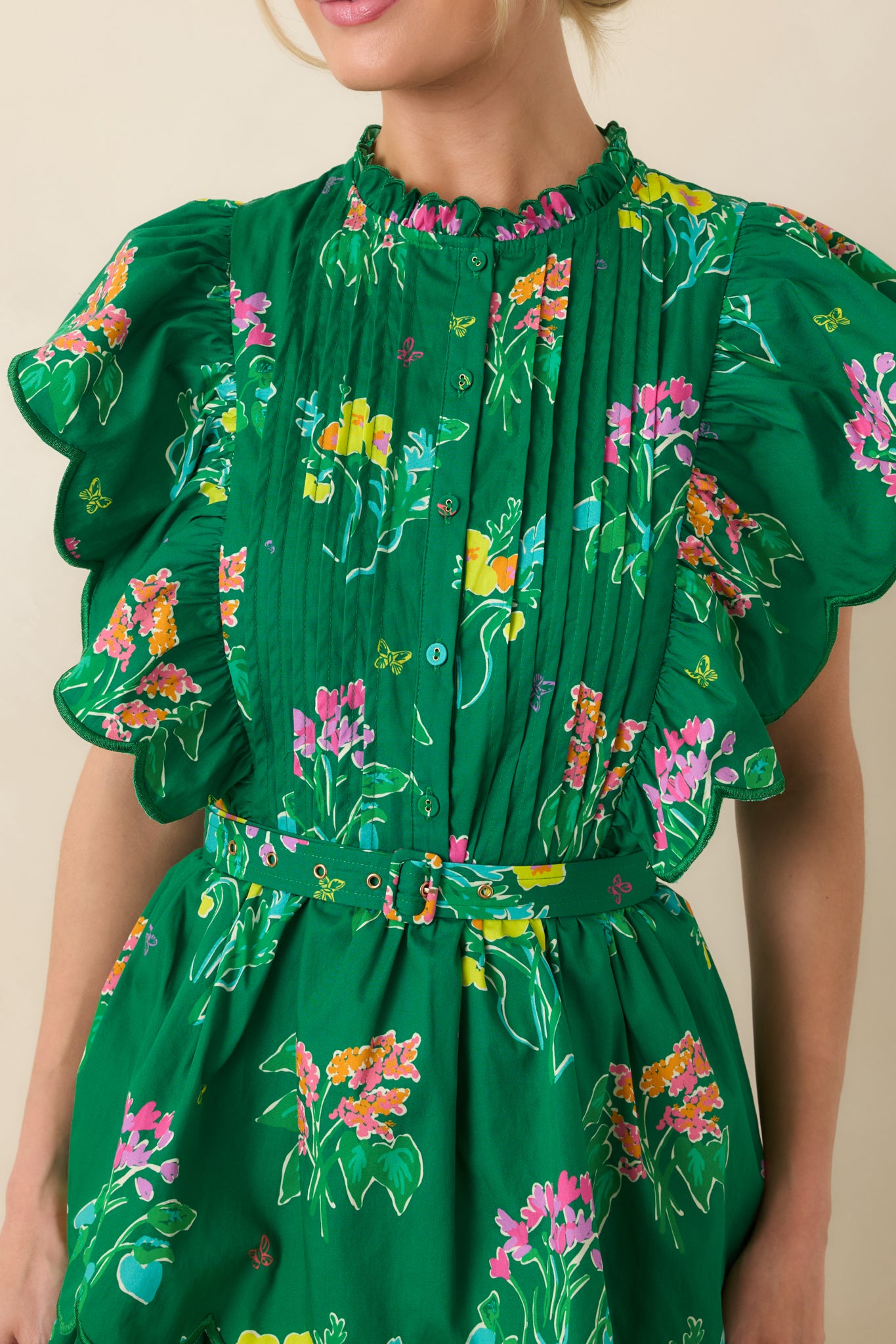 Close-up of pleated bodice, delicate ruffle neckline, and coordinating waist belt on floral cotton dress.