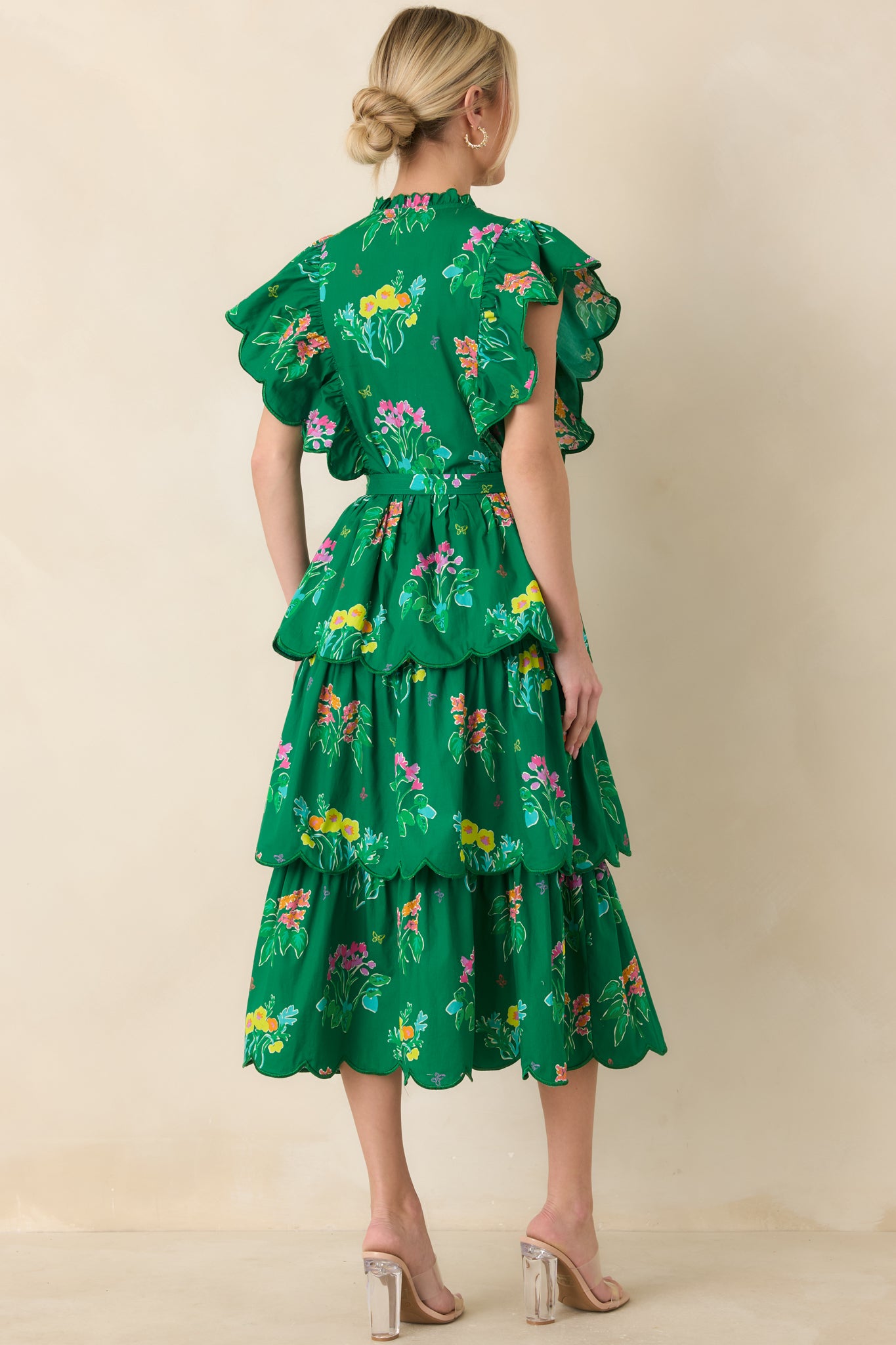 Rear view of midi dress showing flutter sleeves, belted waist, and scalloped tiered ruffles along the skirt.