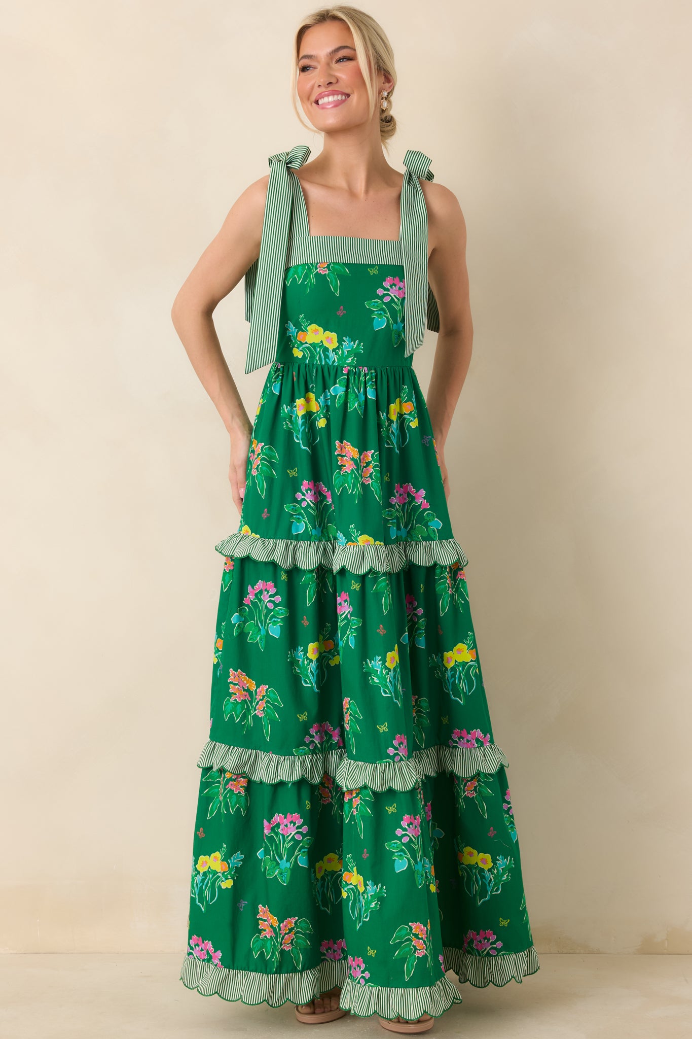 Green floral maxi dress with flowing tiered silhouette and playful adjustable shoulder ties.