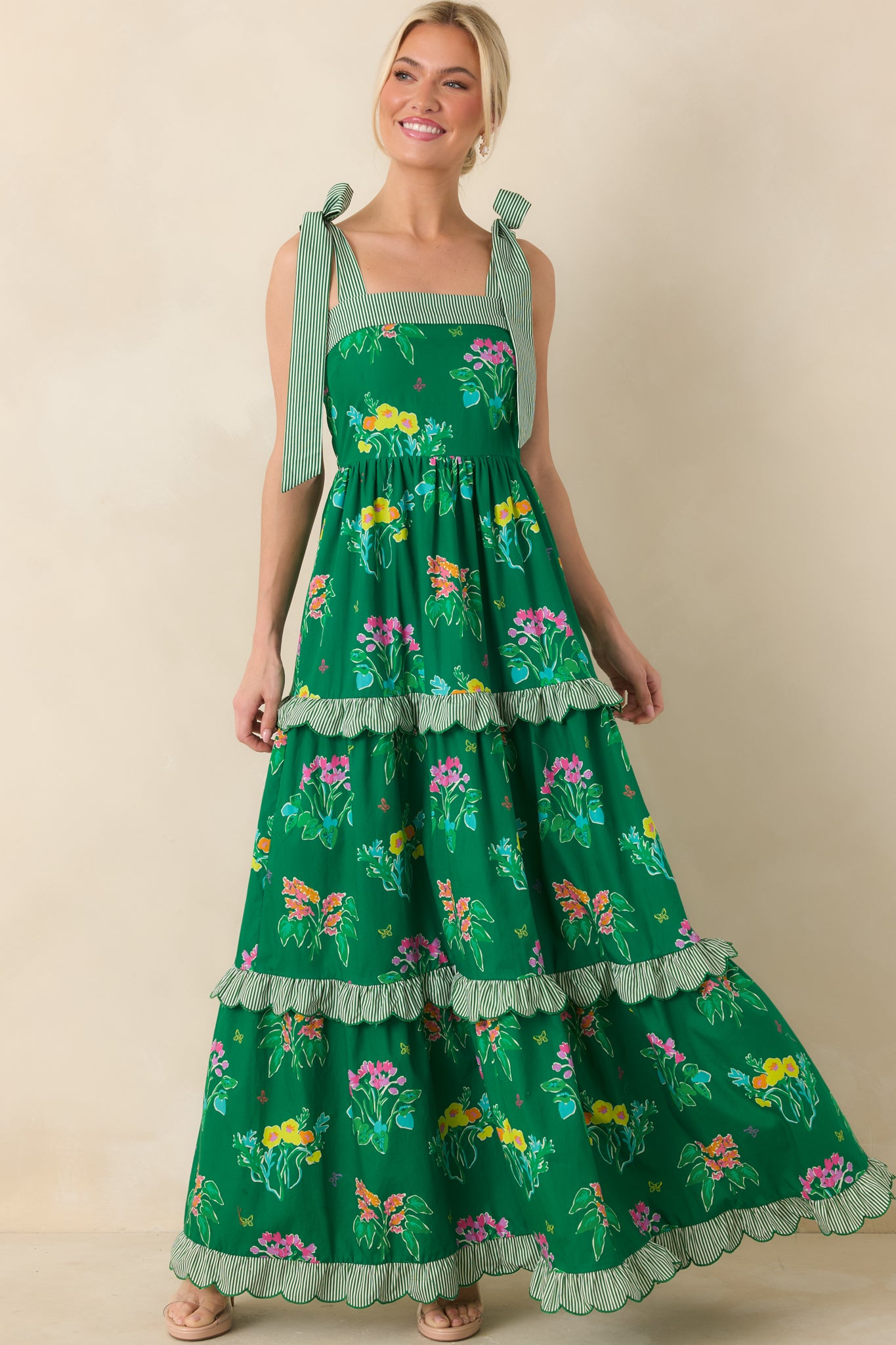 Flowing green floral maxi highlighted by square neckline, adjustable ties, and scalloped tier details.