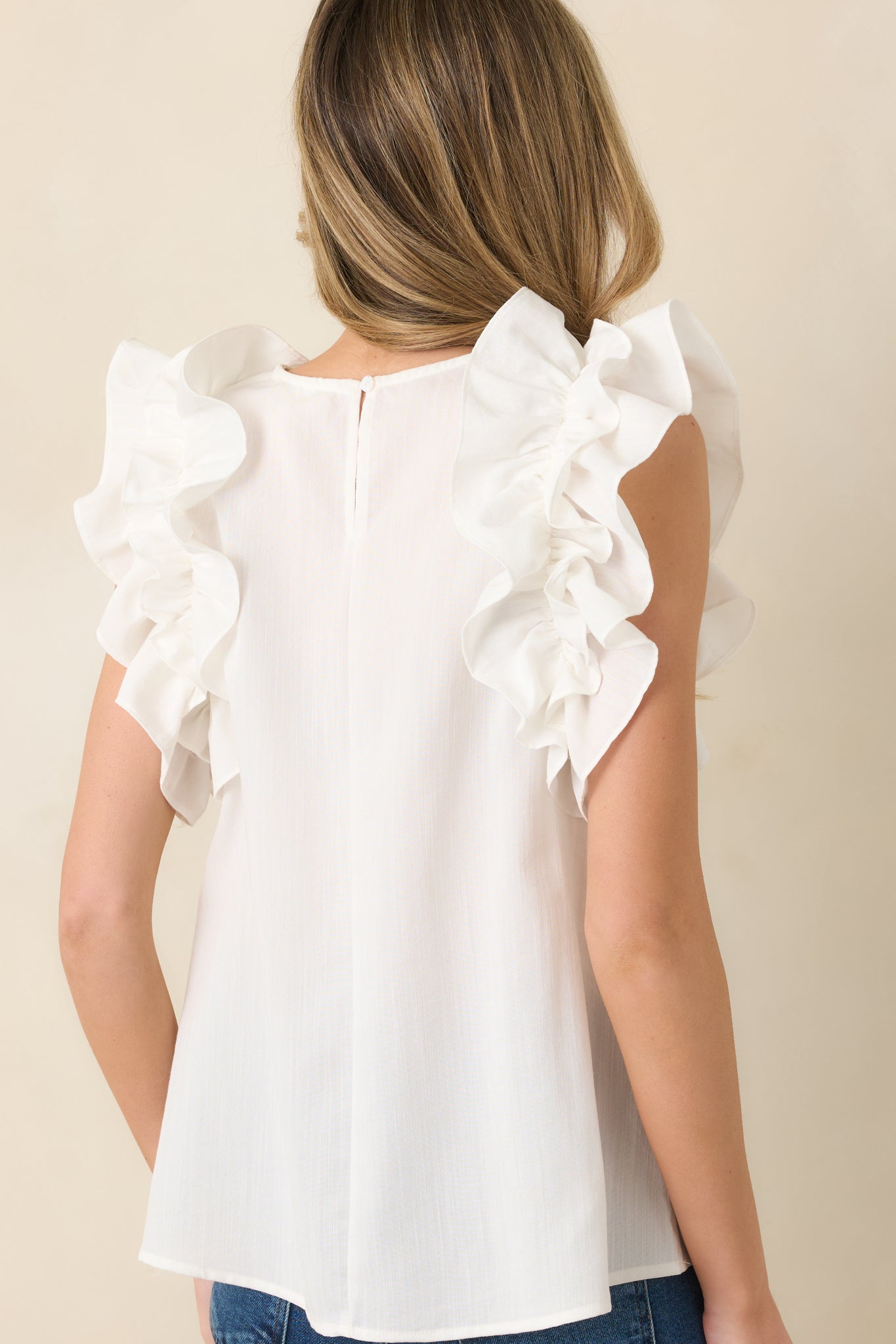 Rear view of ivory top featuring keyhole opening with button closure at neckline.