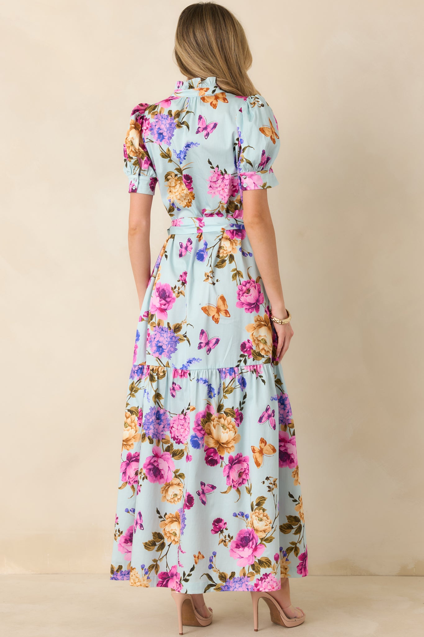 Back view of the blue maxi dress displaying the tiered skirt, smooth back panel, and puff sleeve design.