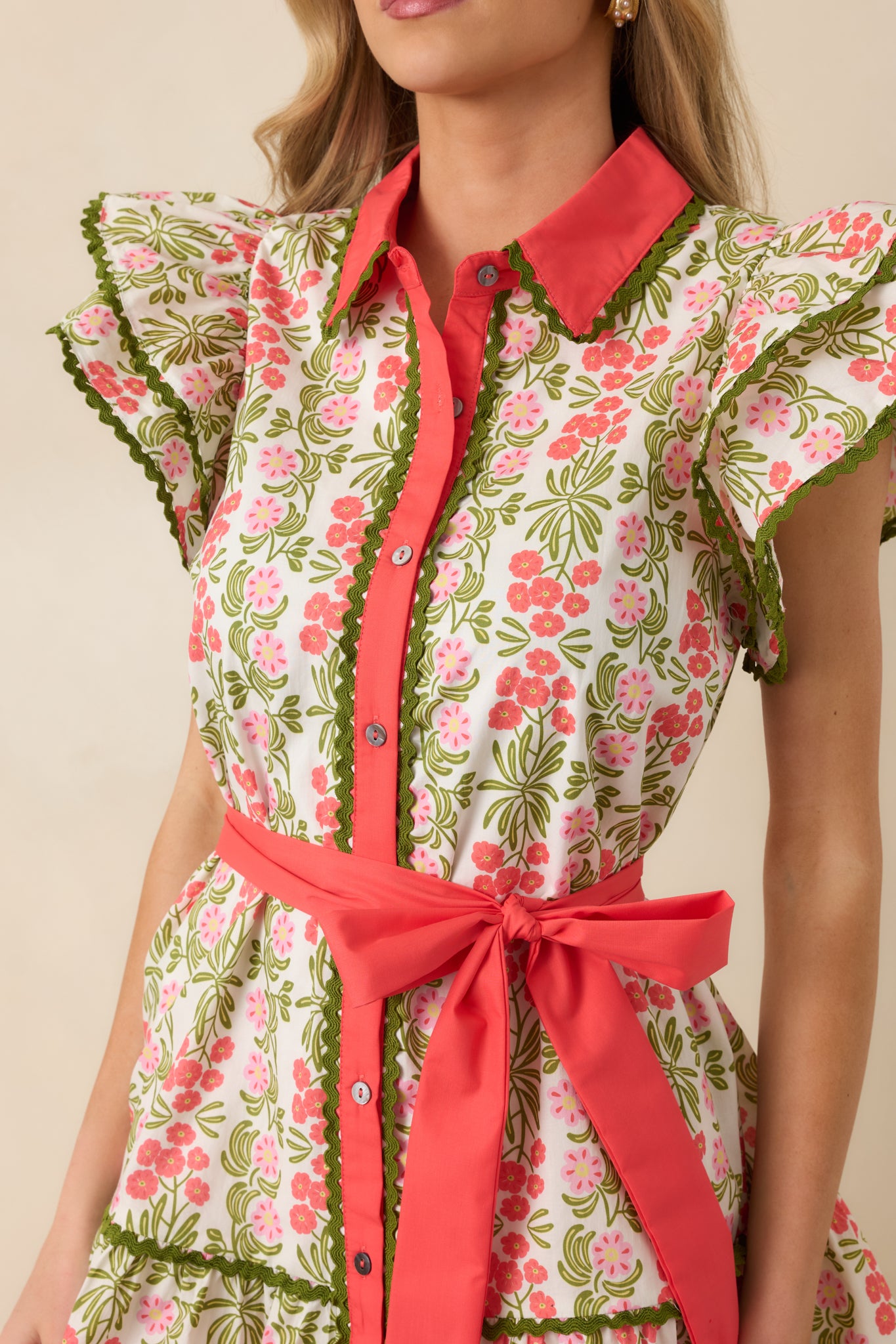 Close-up of the coral pink mini dress showing the floral print fabric and textured green ric rac trim.