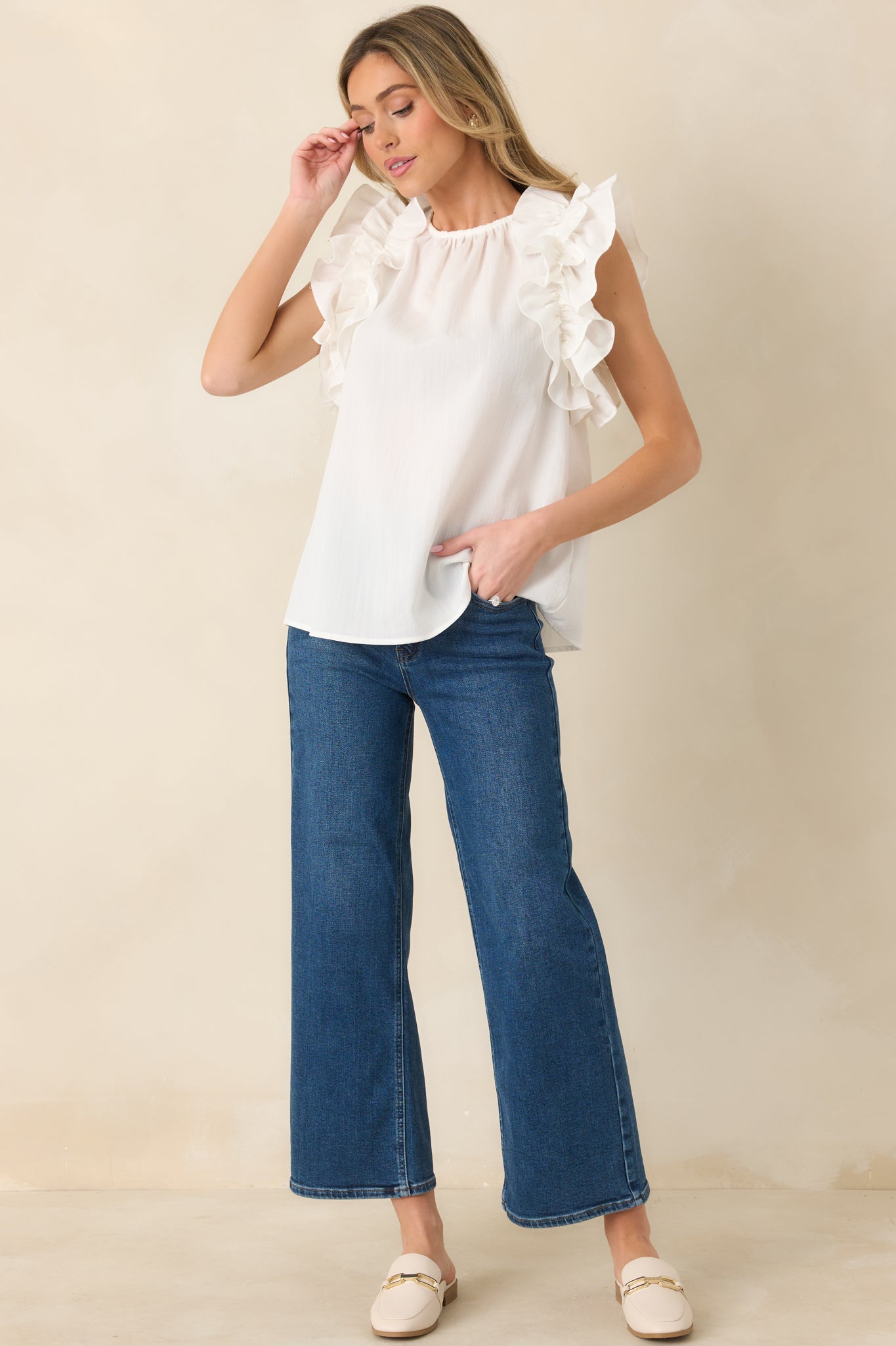 Elegant ivory top with elevated neckline and feminine ruffle trim.