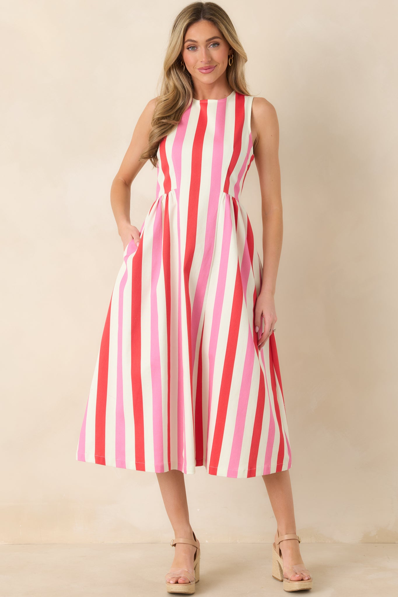 Front view of pink multi sleeveless midi dress featuring vertical pink and red stripes, fitted bodice, and full A-line skirt.