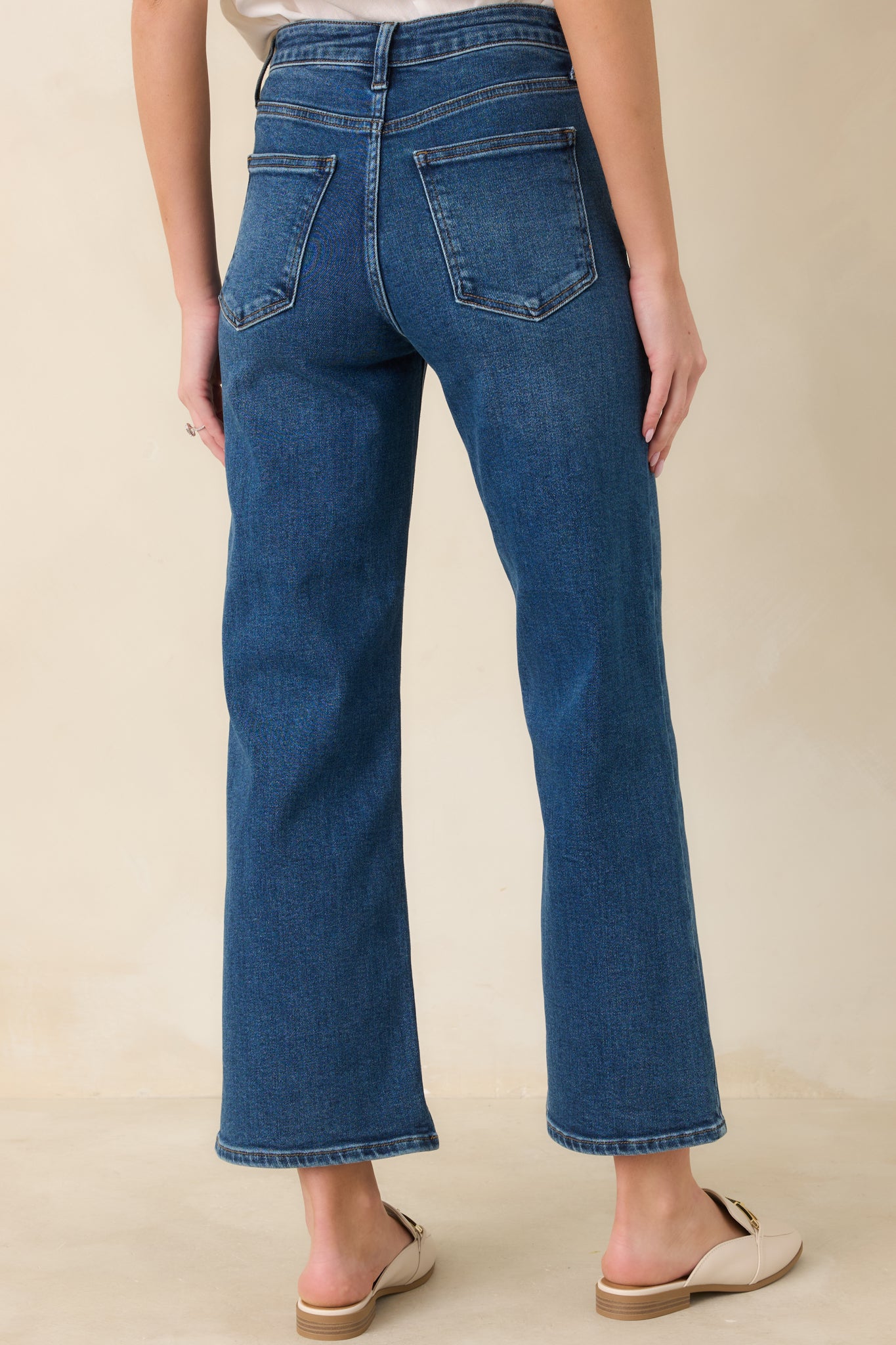 Back view of dark wash jeans highlighting rear pockets and structured high-waisted silhouette.