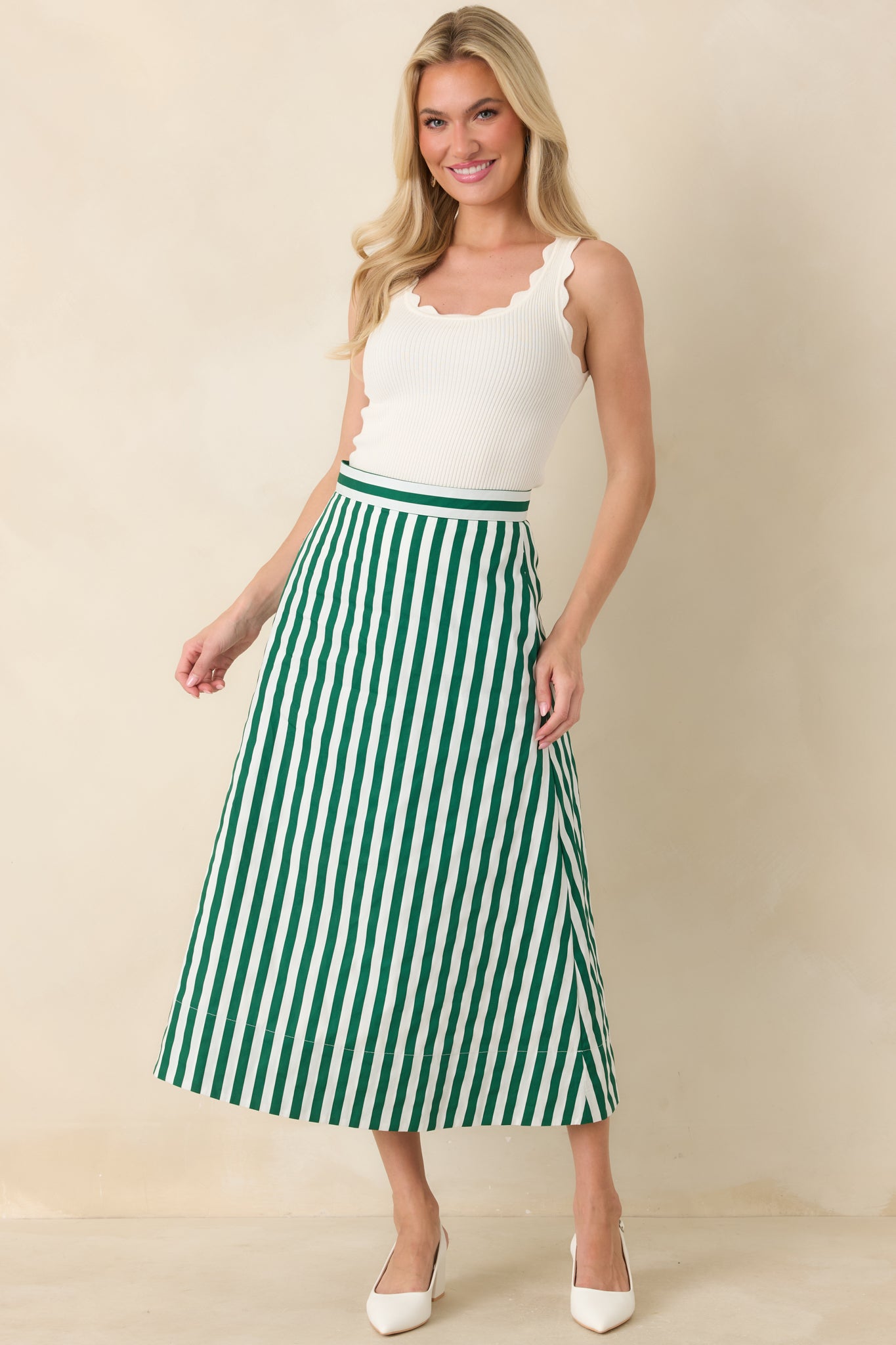Tailored midi skirt featuring vertical green and ivory stripes, a smooth waistband, and a classic A-line shape with functional pockets.