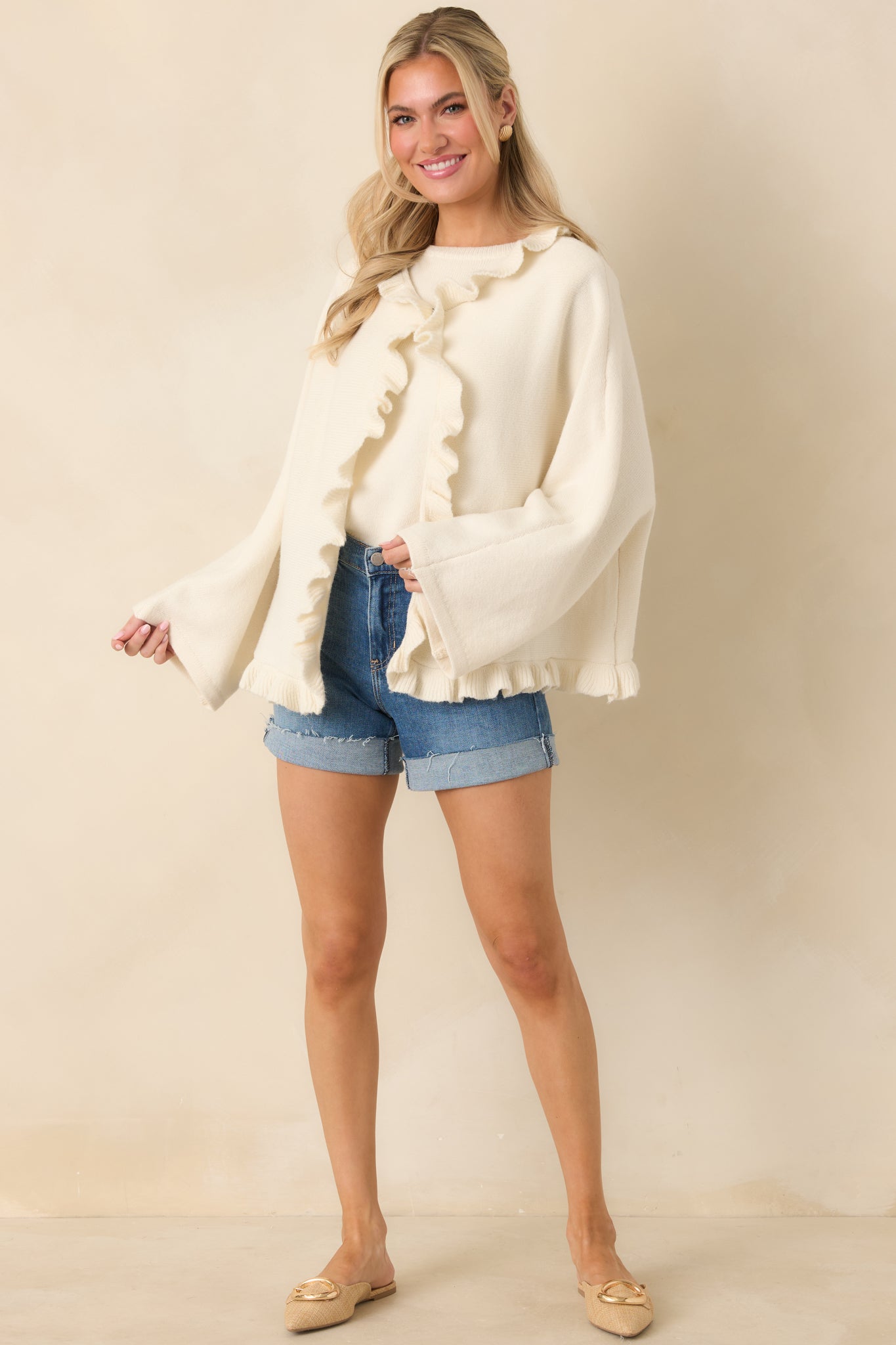 Full-length front view of the ivory cardigan showcasing the open-front design and cascading ruffle details along the placket and hem.