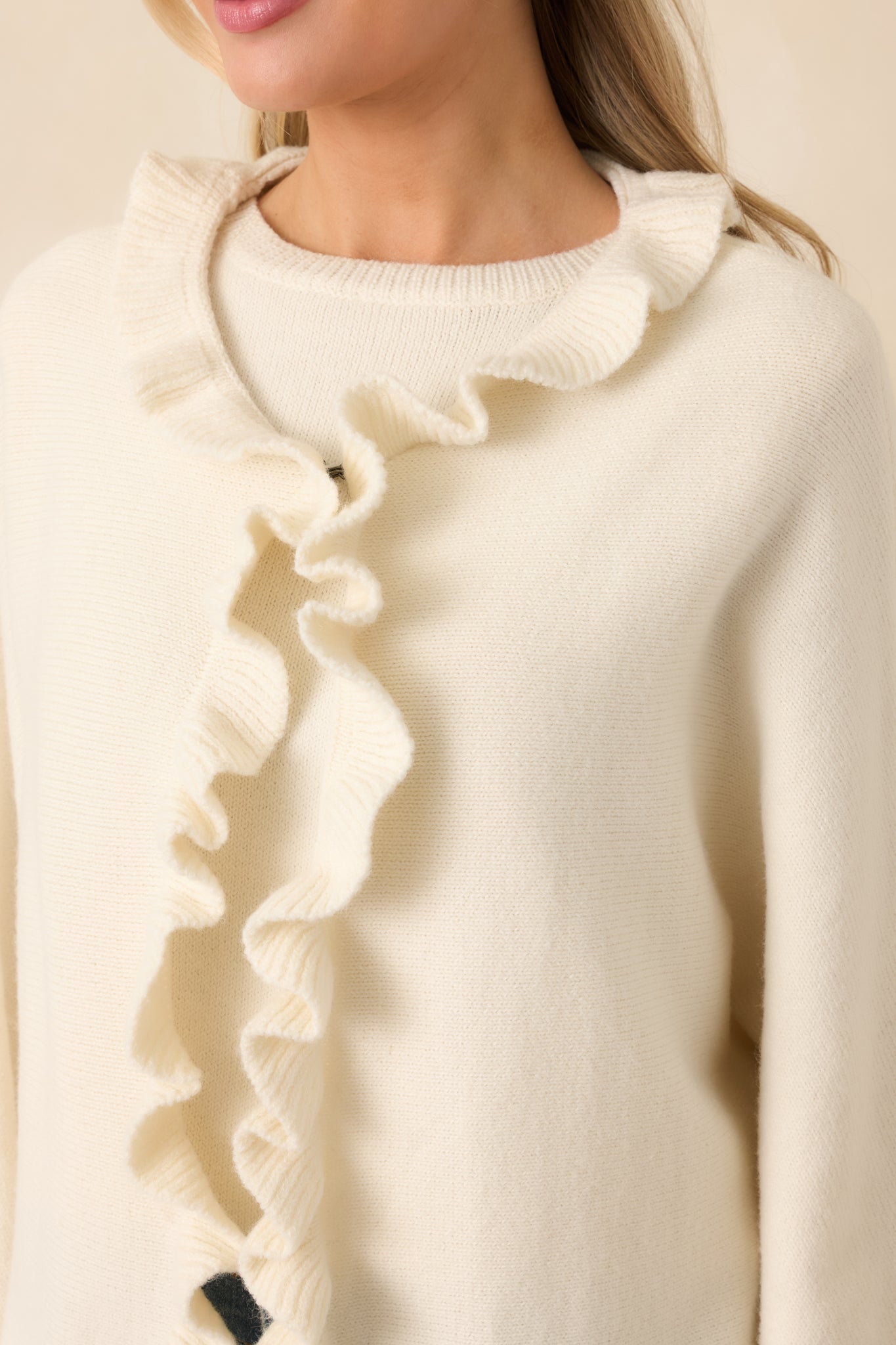 Close-up view of the ivory cardigan emphasizing the cascading ruffle trim along the placket and hem.