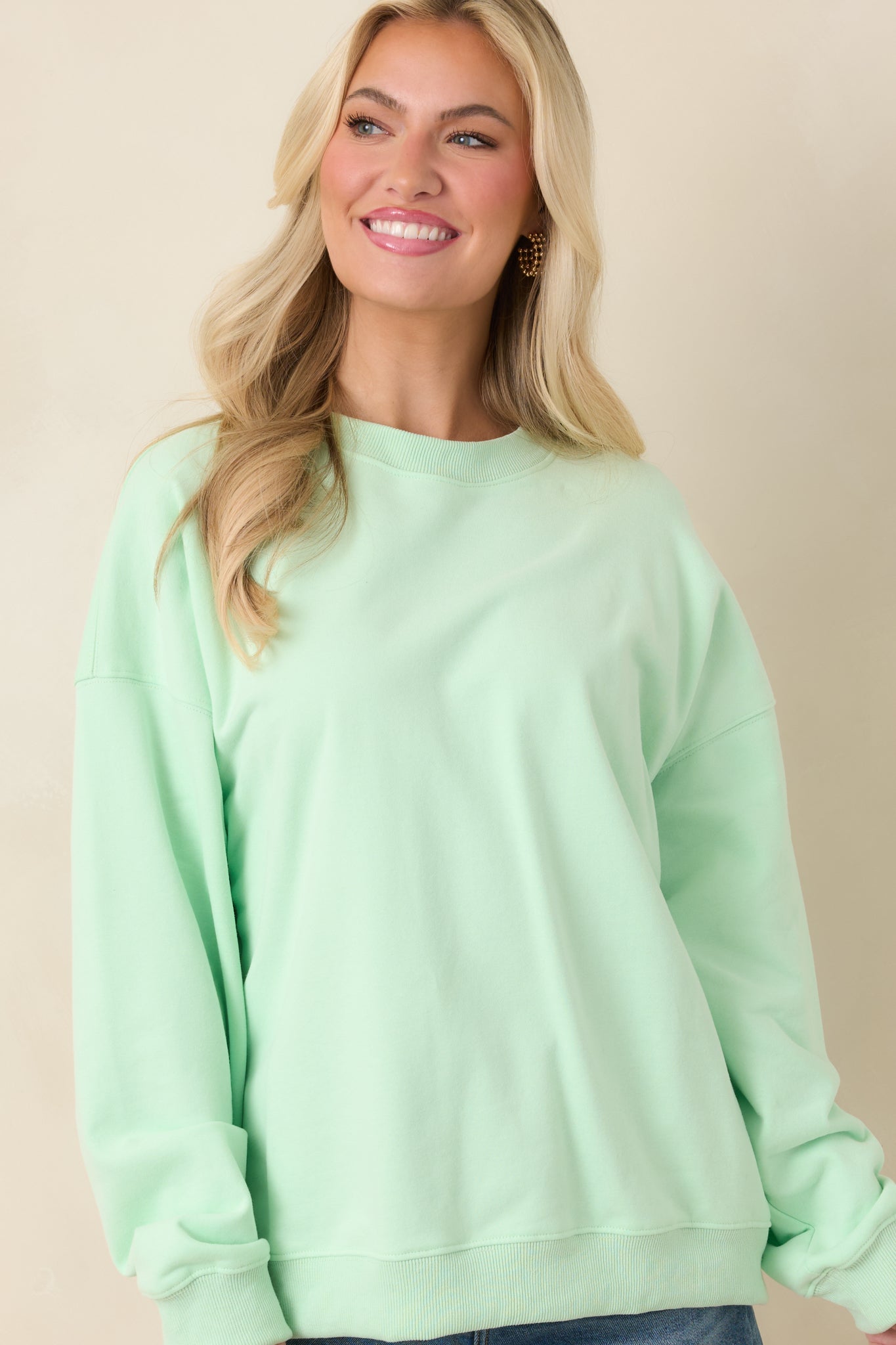 Close front crop highlighting long sleeves and relaxed fit of mint green sweatshirt.