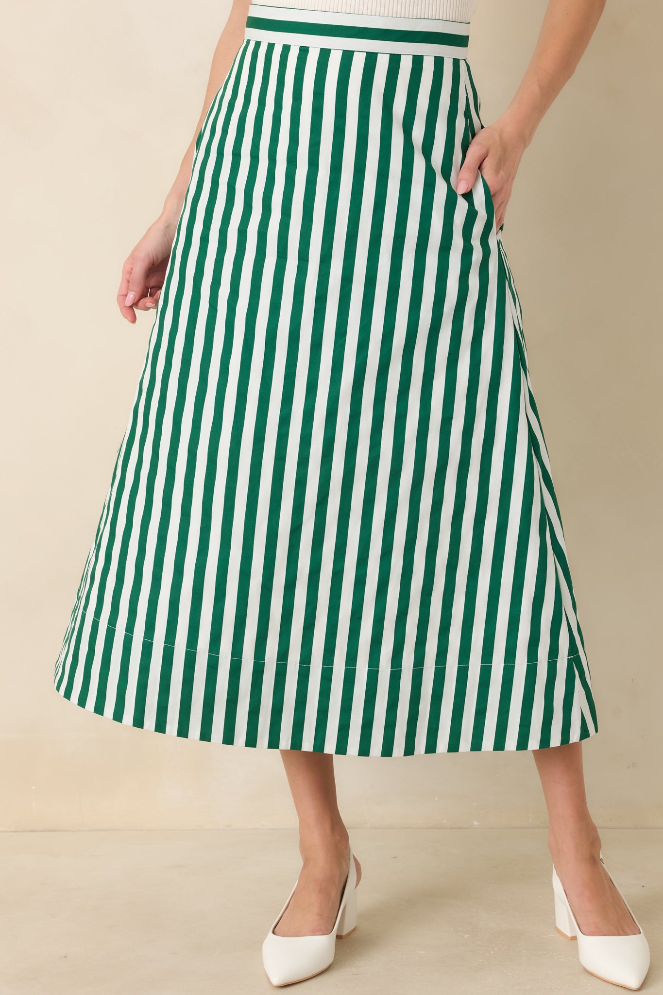 Detailed view of the vertical green and ivory stripes with the skirt’s softly flared silhouette and pocket placement.