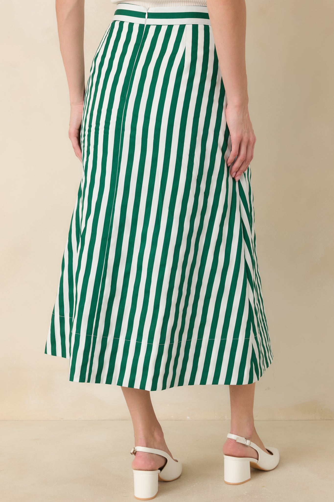 Rear view of the midi skirt featuring the vertical green and ivory stripes and a concealed zipper for a streamlined finish.