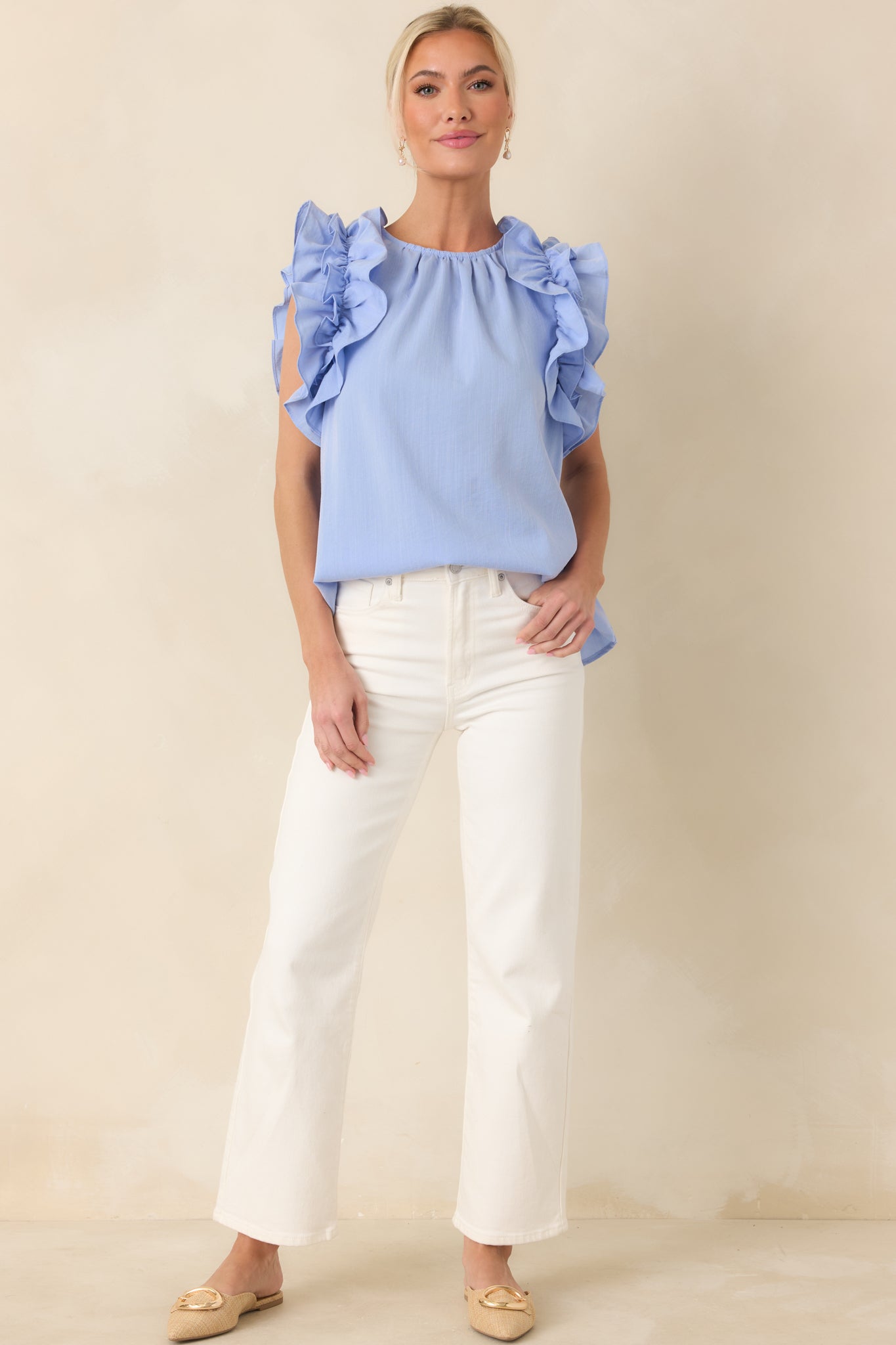Soft light blue blouse featuring structured crew neck and layered ruffle shoulders.