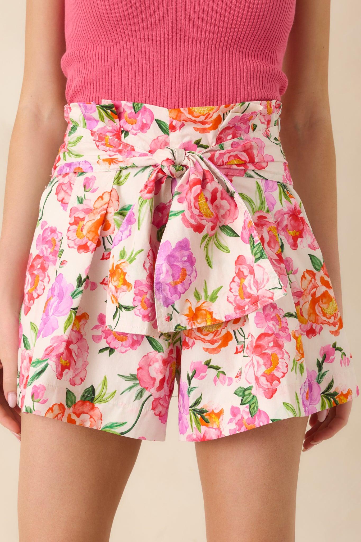 High-waisted floral shorts with a wide waistband and bold pink botanical pattern.