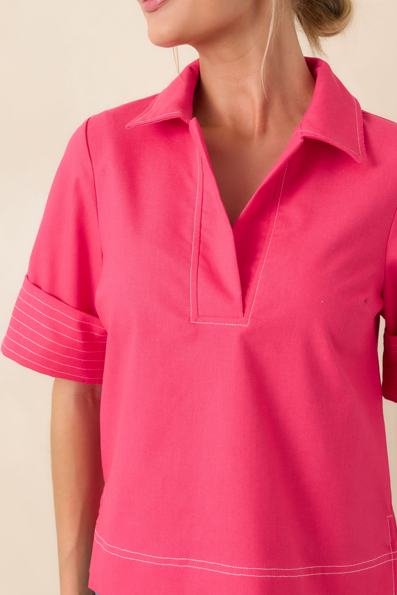 Close-up of hot pink fabric showcasing contrast stitching and structured collar construction.