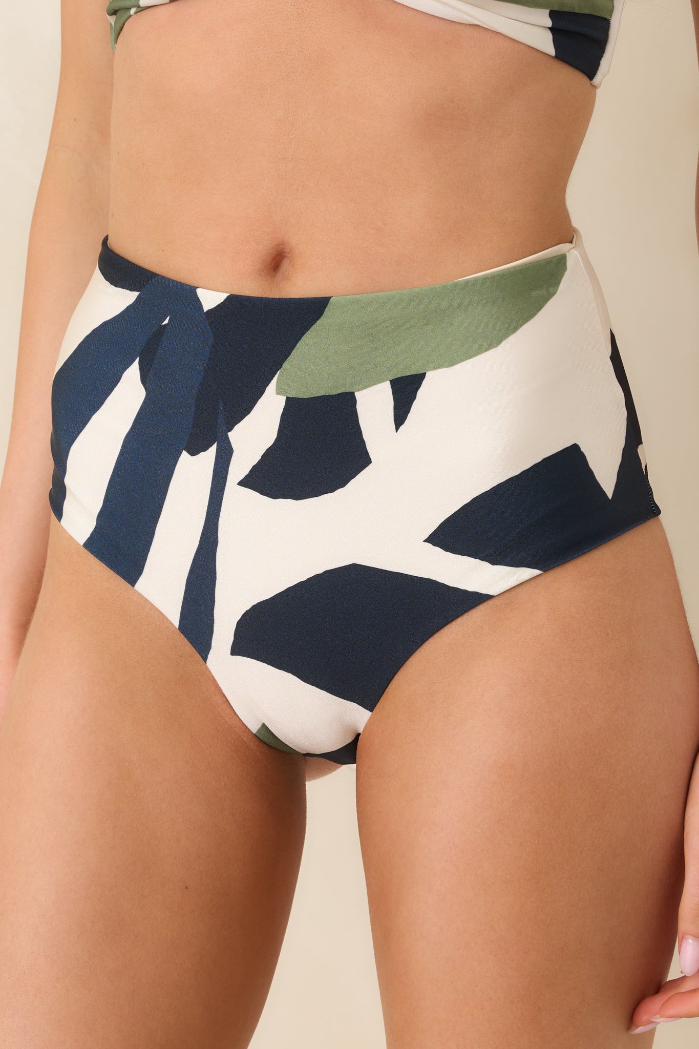 Close-up of fabric texture and intricate green and blue palm leaf pattern on creamy base.