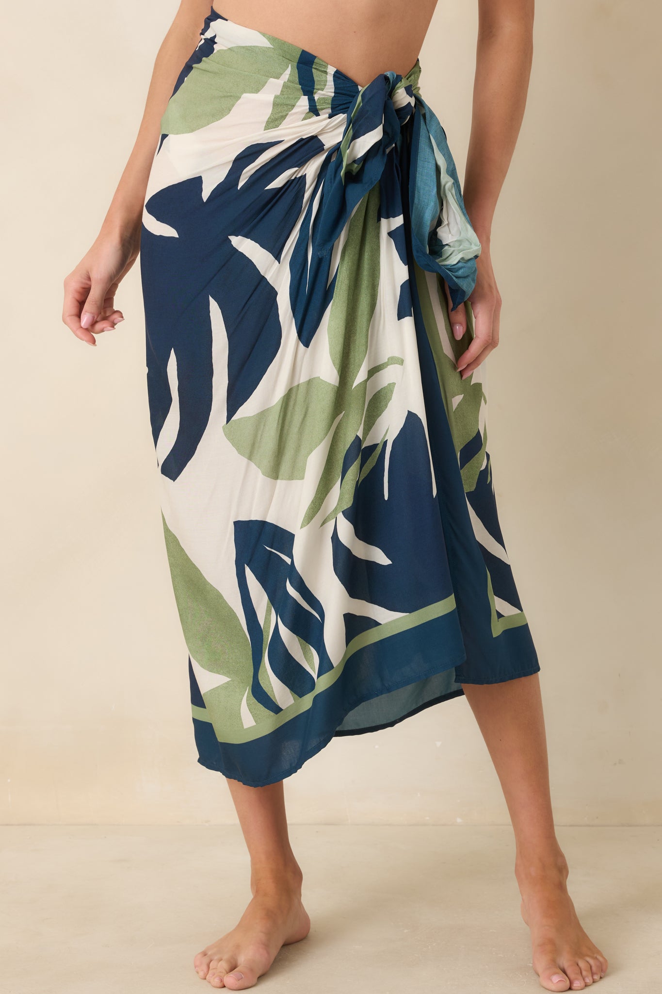 Close view of palm leaf print sarong showing navy and sage botanical pattern on neutral fabric.