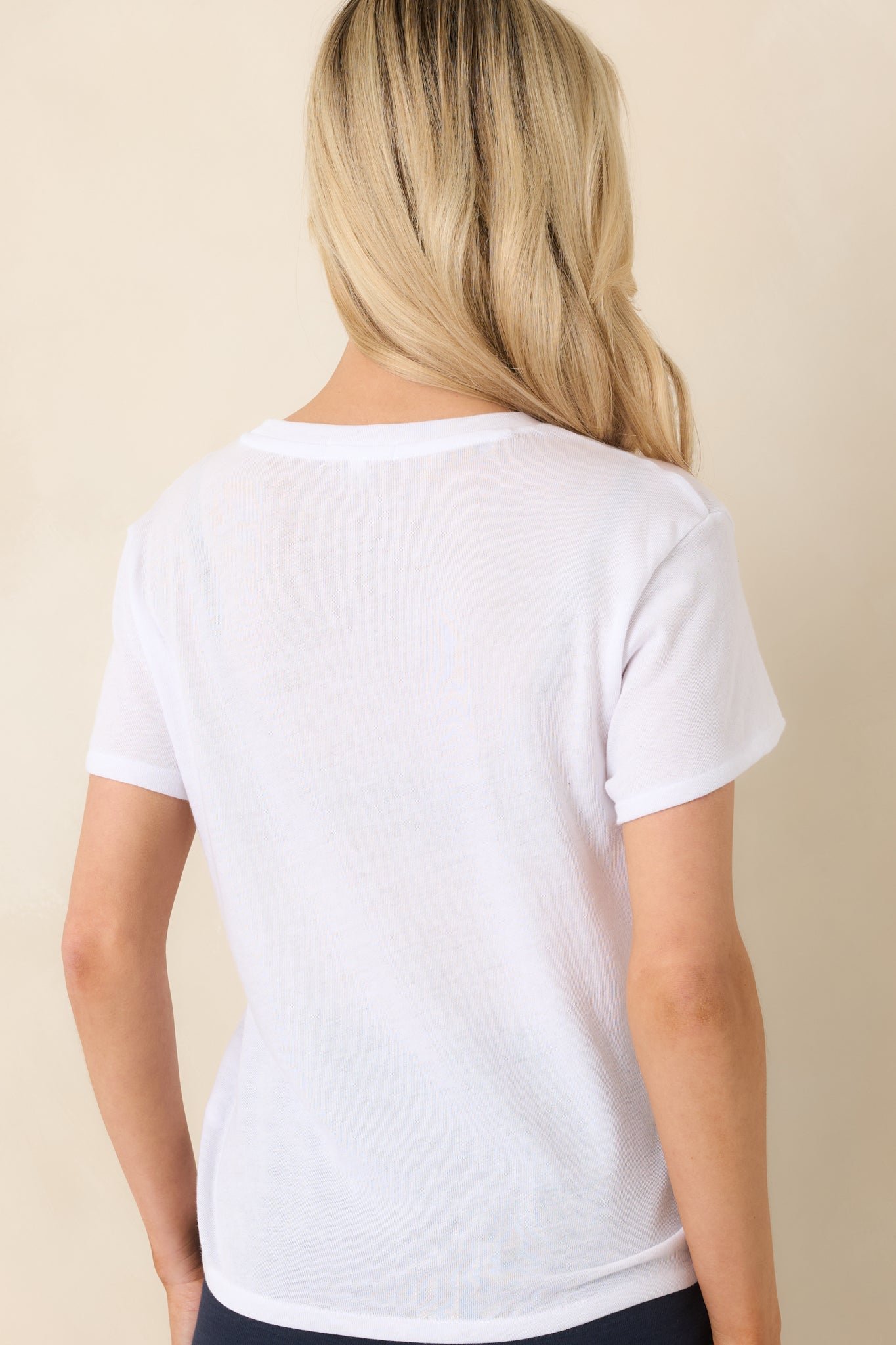 Back view of white tee highlighting smooth jersey fabric and curved hemline.