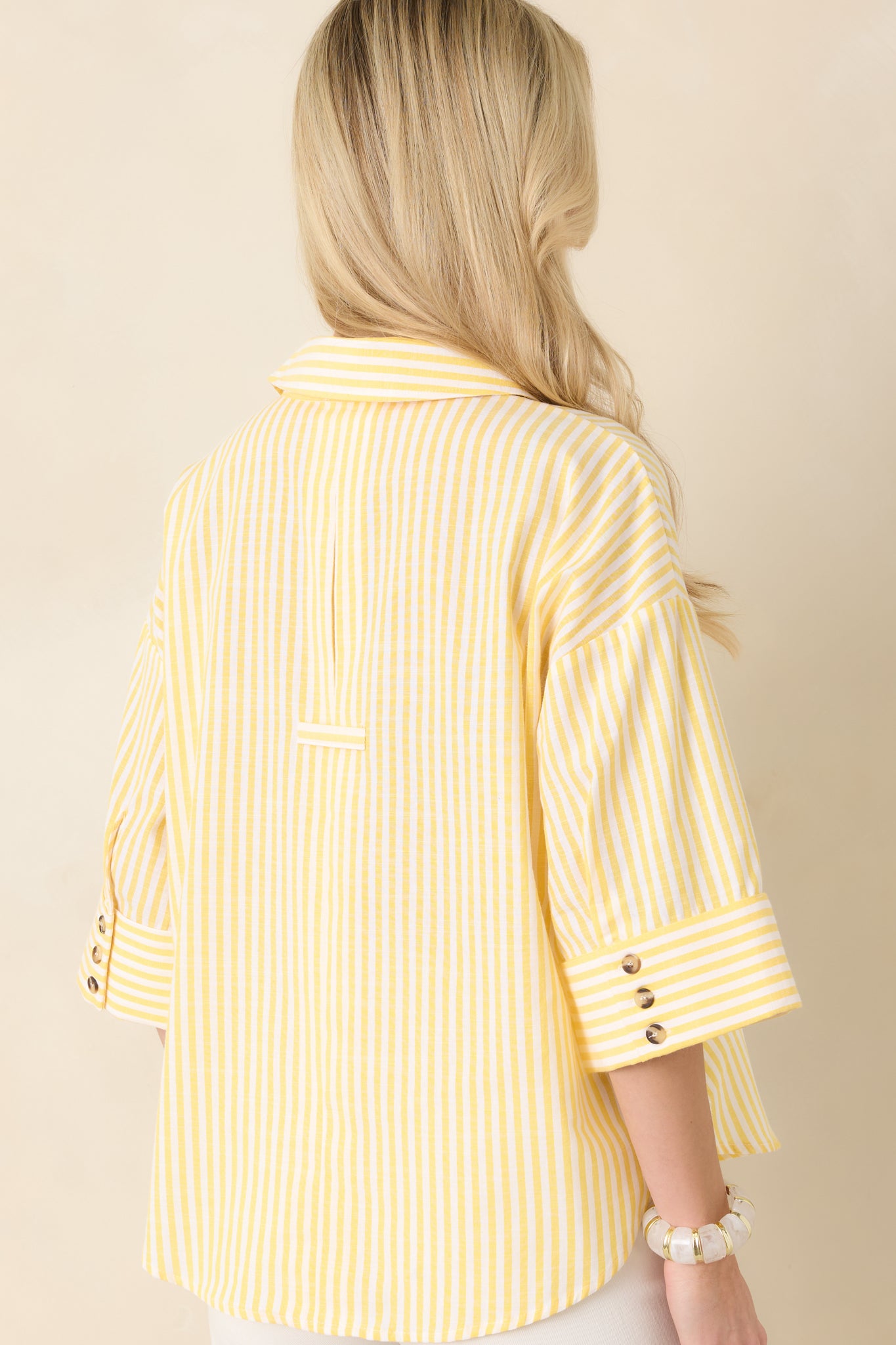 Back view of the yellow and white striped blouse featuring relaxed fit and continued vertical stripe pattern.