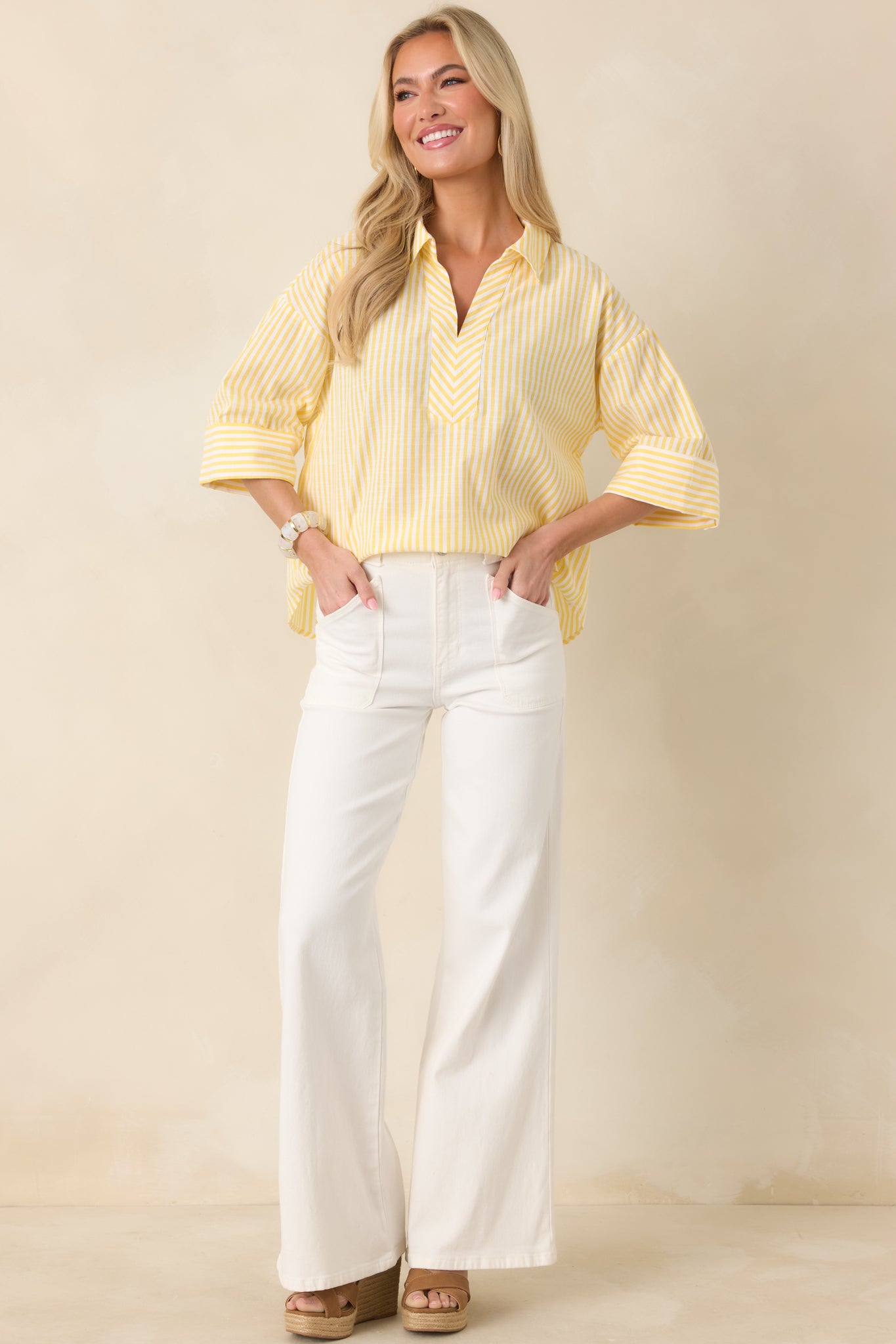 Full-body view of the yellow and white striped blouse highlighting its slightly oversized silhouette and curved hemline.