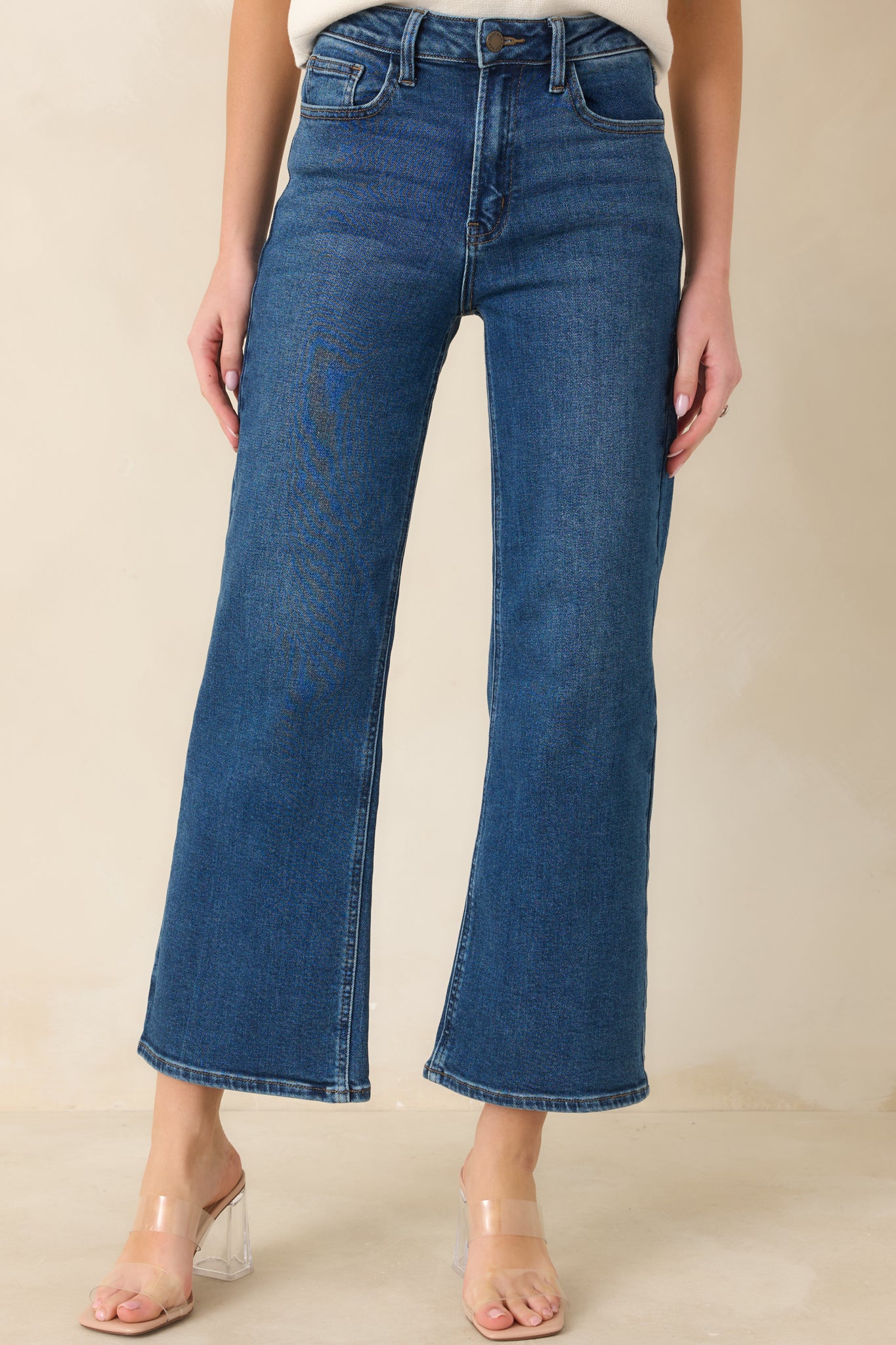 Close-up of dark wash jeans featuring the metal button, zipper fly, and reinforced belt loops.