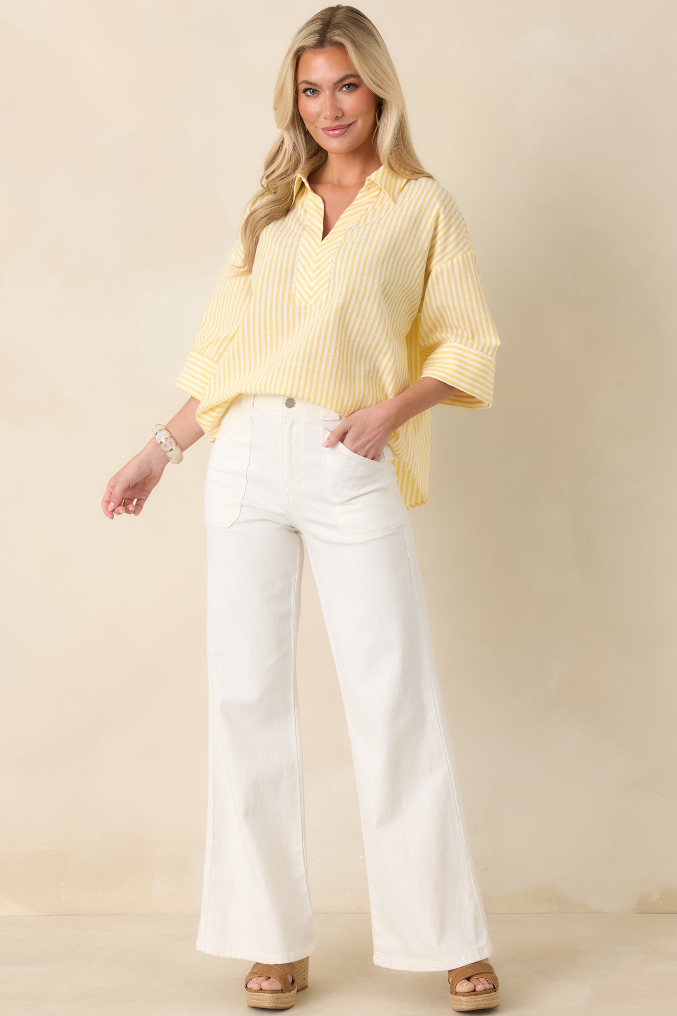 Full-body view showing the striped blouse styled untucked, featuring crisp lines and modern tailoring.
