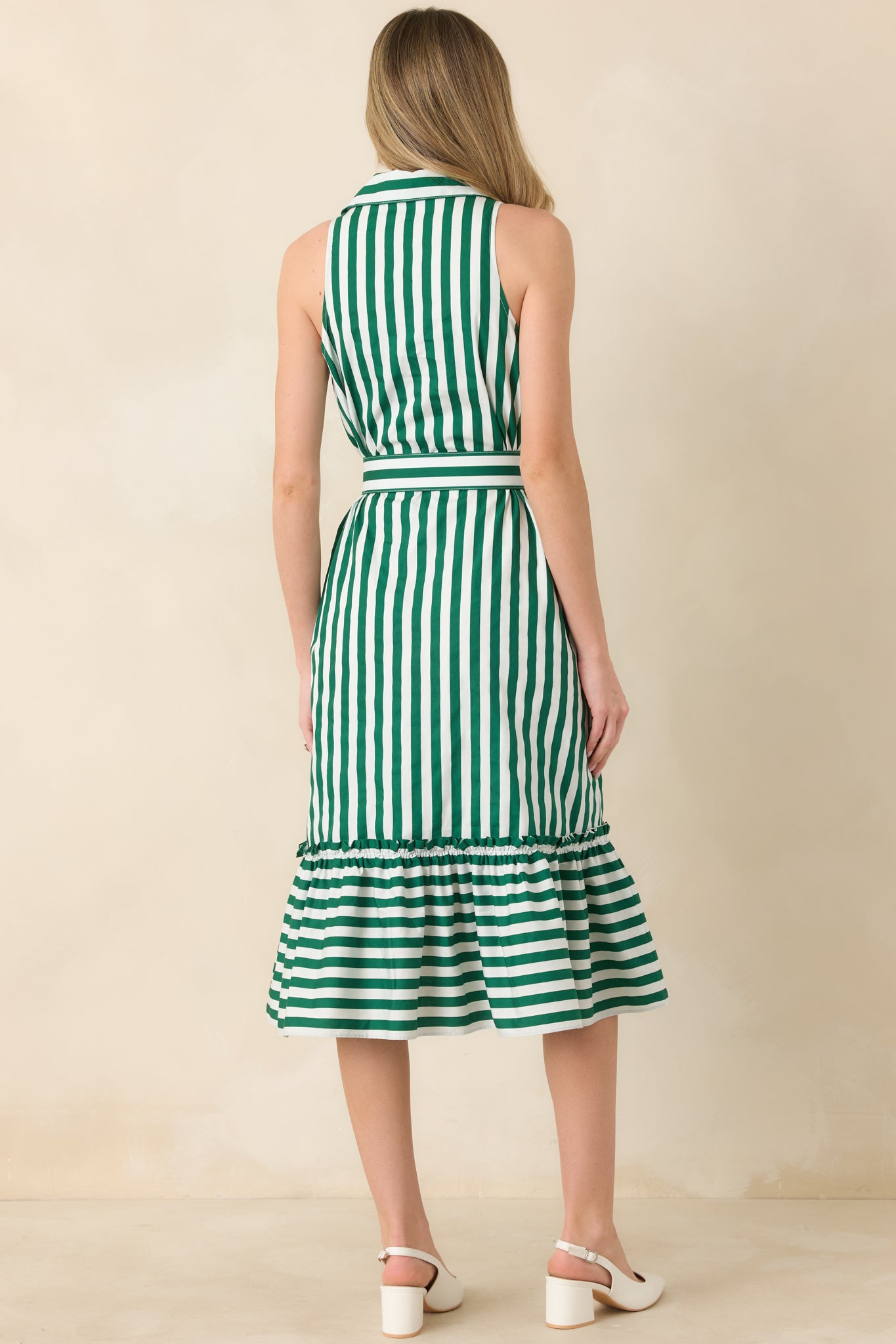 Rear view of the striped midi dress featuring vertical green and ivory stripes and a softly gathered ruffle hem flowing from the defined waist.