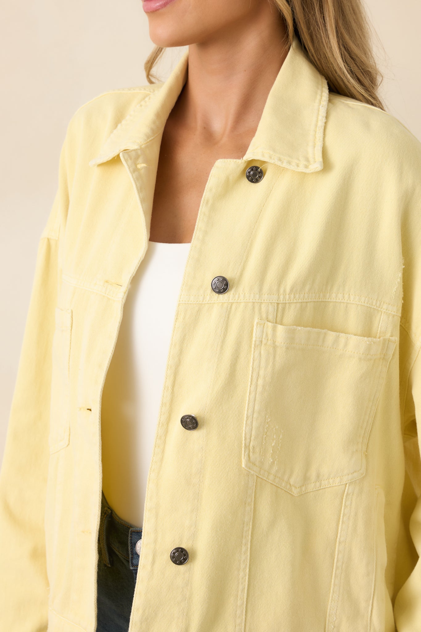 Close look at the metal buttons, reinforced stitching, and structured collar that define this classic denim jacket.