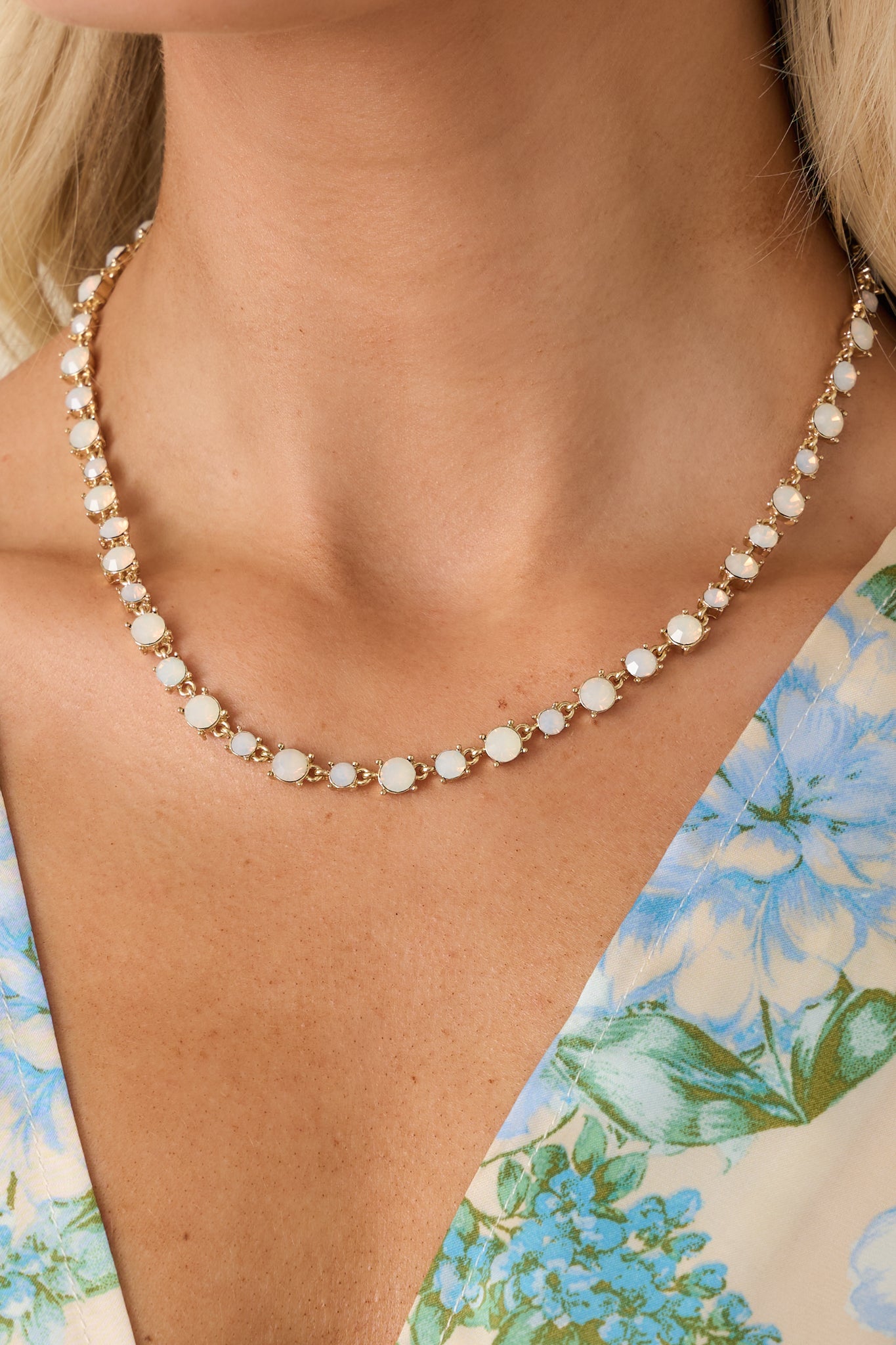 Close-up of gold-tone necklace detailing bezel-set opal stones and polished chain links.