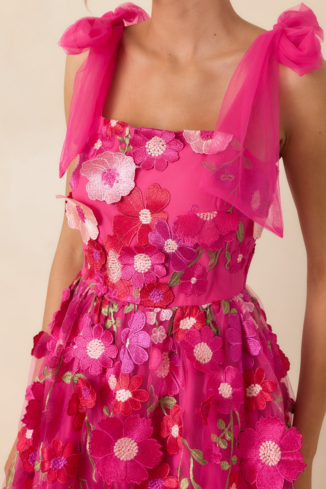 Close-up of the fuchsia dress bodice showcasing three-dimensional floral appliqués and embroidery texture.