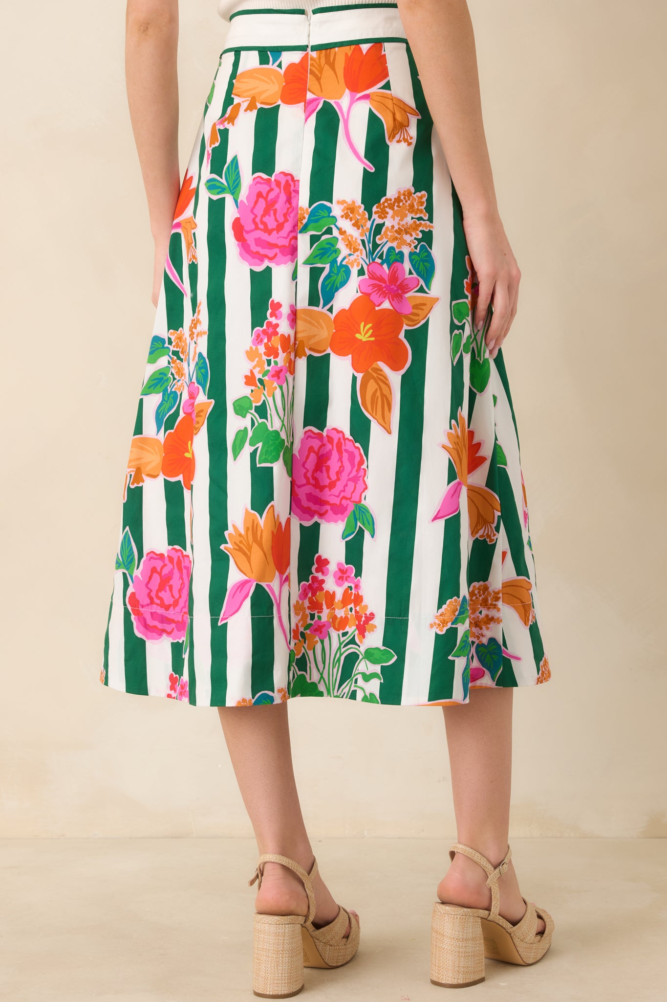 Rear view of the midi skirt showcasing the green vertical stripes, floral pattern, and graceful, structured drape.