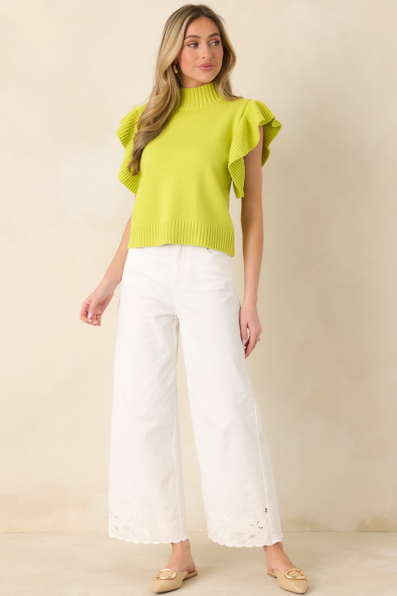 Knitted yellow-green top with a ribbed mock neck, flowing flutter sleeves, and a relaxed fit finished with a textured hem.